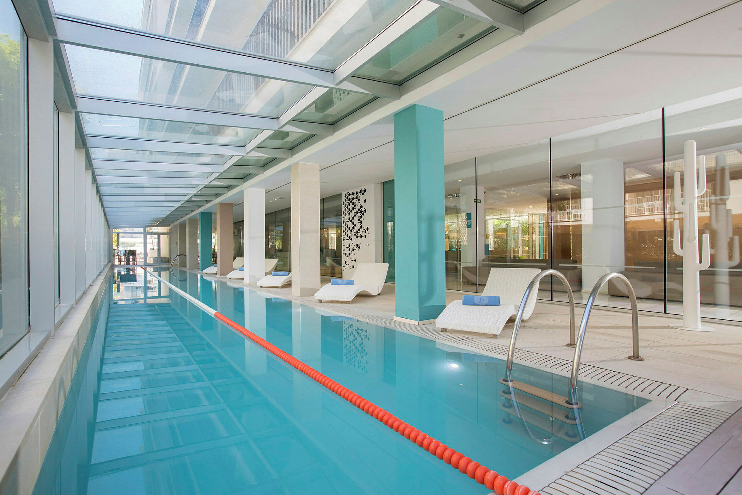 En indendørs swimmingpool med liggestole ved siden af. (AI-genereret tekst)