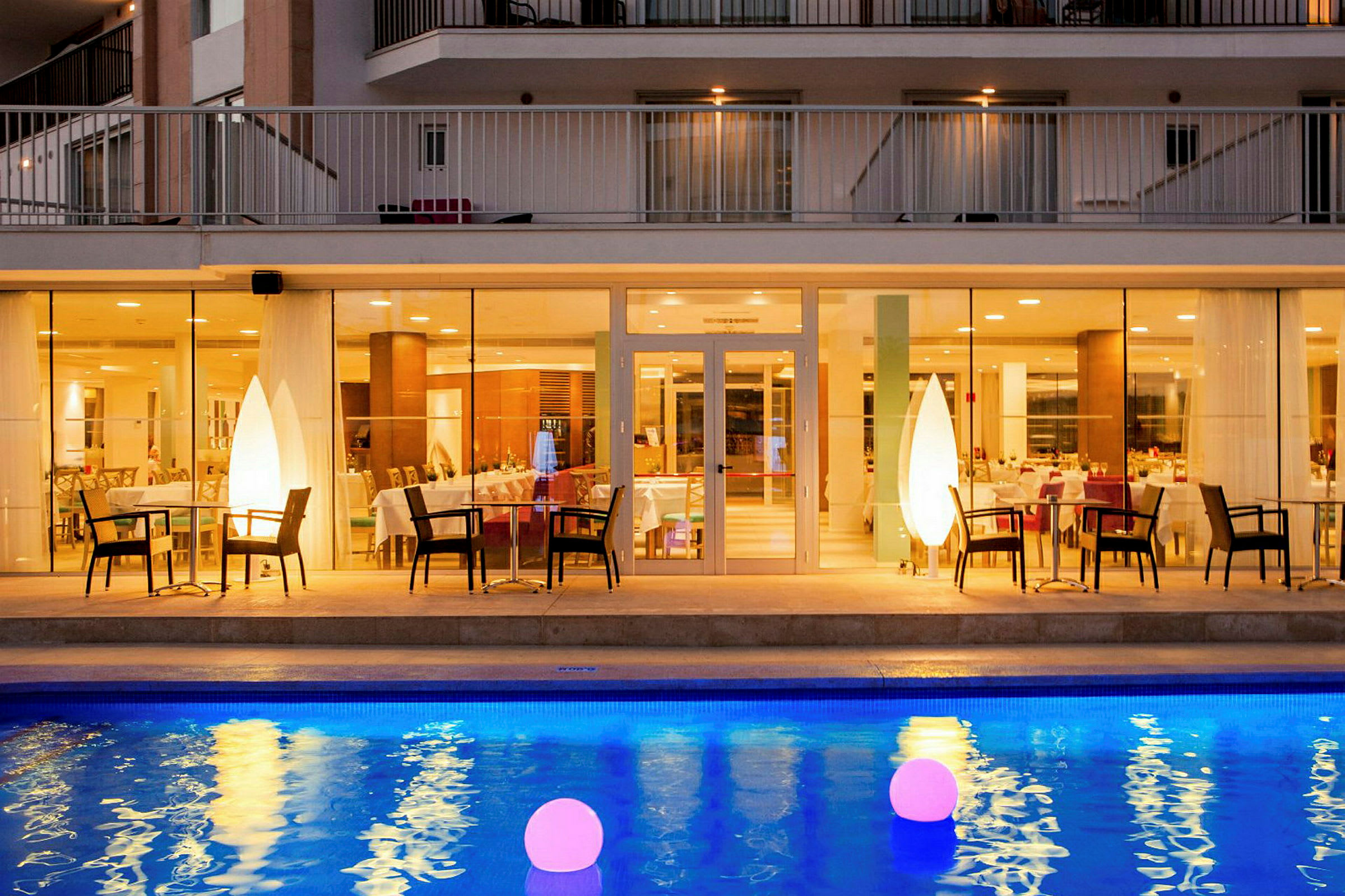 Hotelrestaurant med oplyst pool i forgrunden. (AI-genereret tekst)
