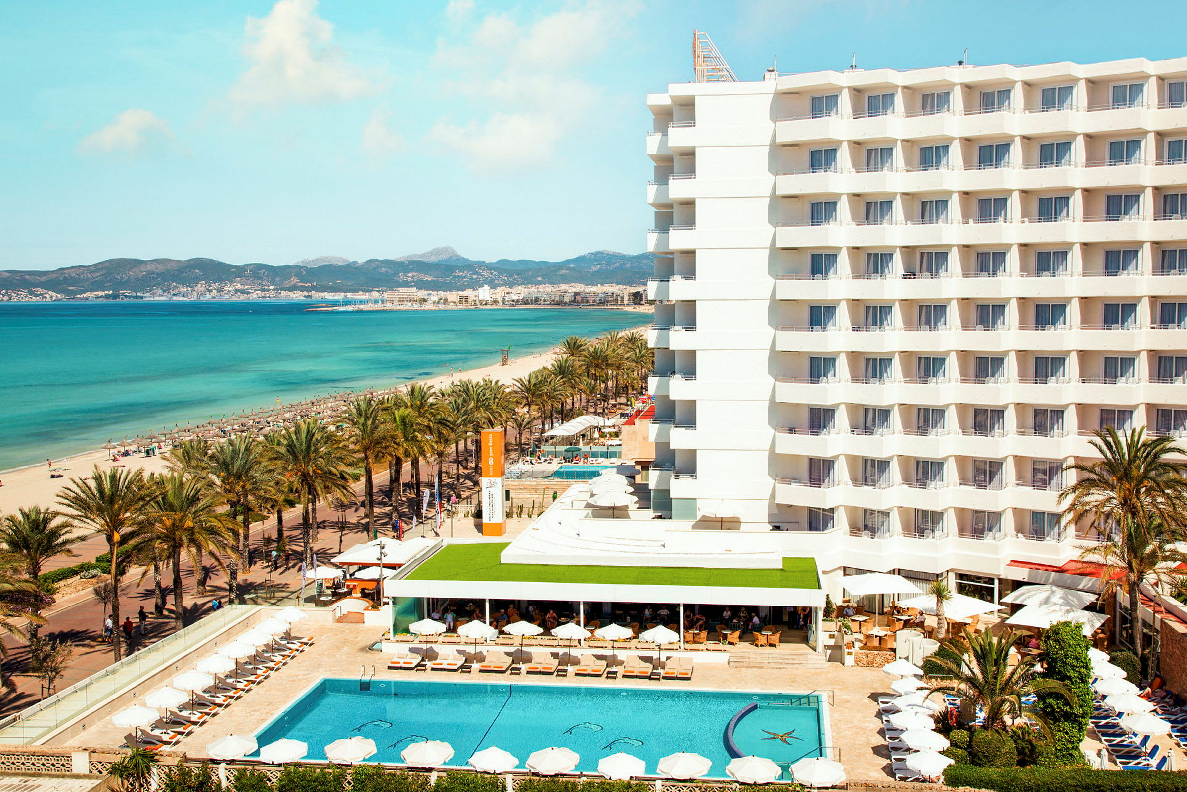 Hotel ved stranden med pool og liggestole, hav i baggrunden. (AI-genereret tekst)