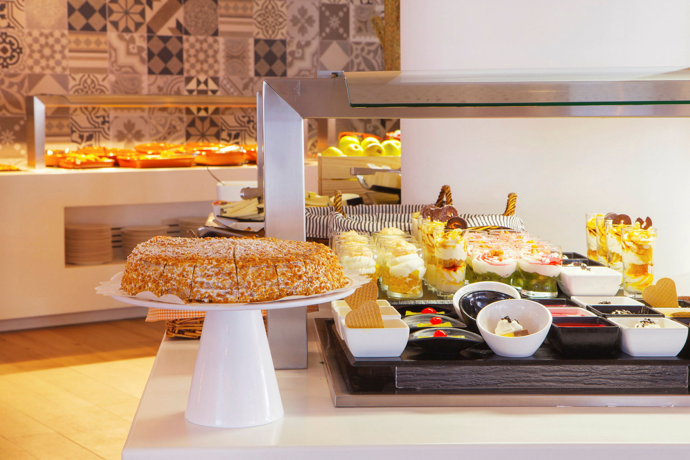 En buffet med desserter, herunder en kage, glas med desserter og små skåle med tilbehør. (AI-genereret tekst)