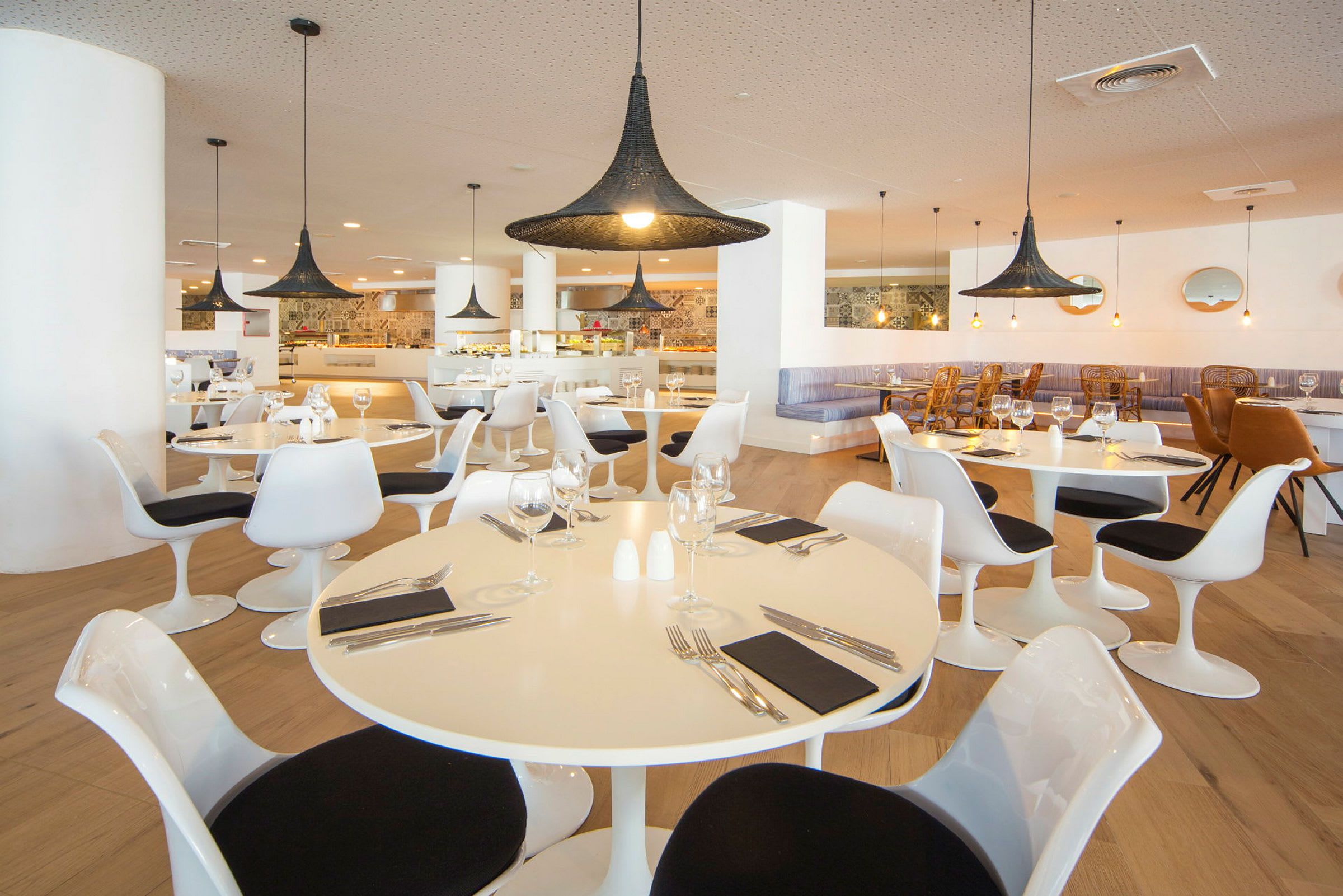 Billede af en restaurant med moderne hvide borde og stole samt store sorte lamper. (AI-genereret tekst)