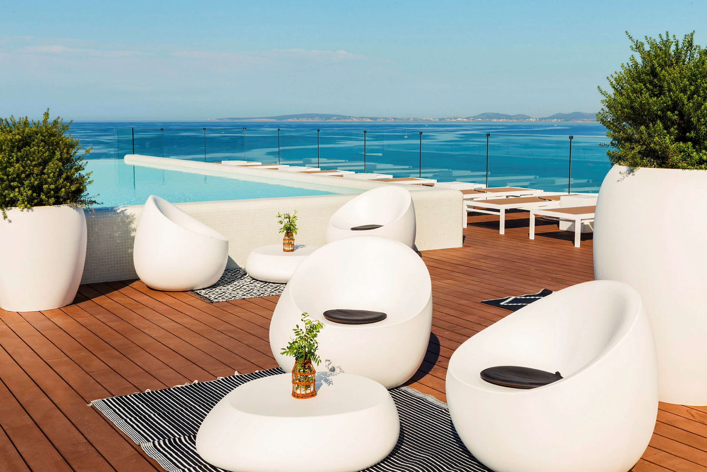 Loungeområde ved en pool med moderne møbler og udsigt over havet. (AI-genereret tekst)