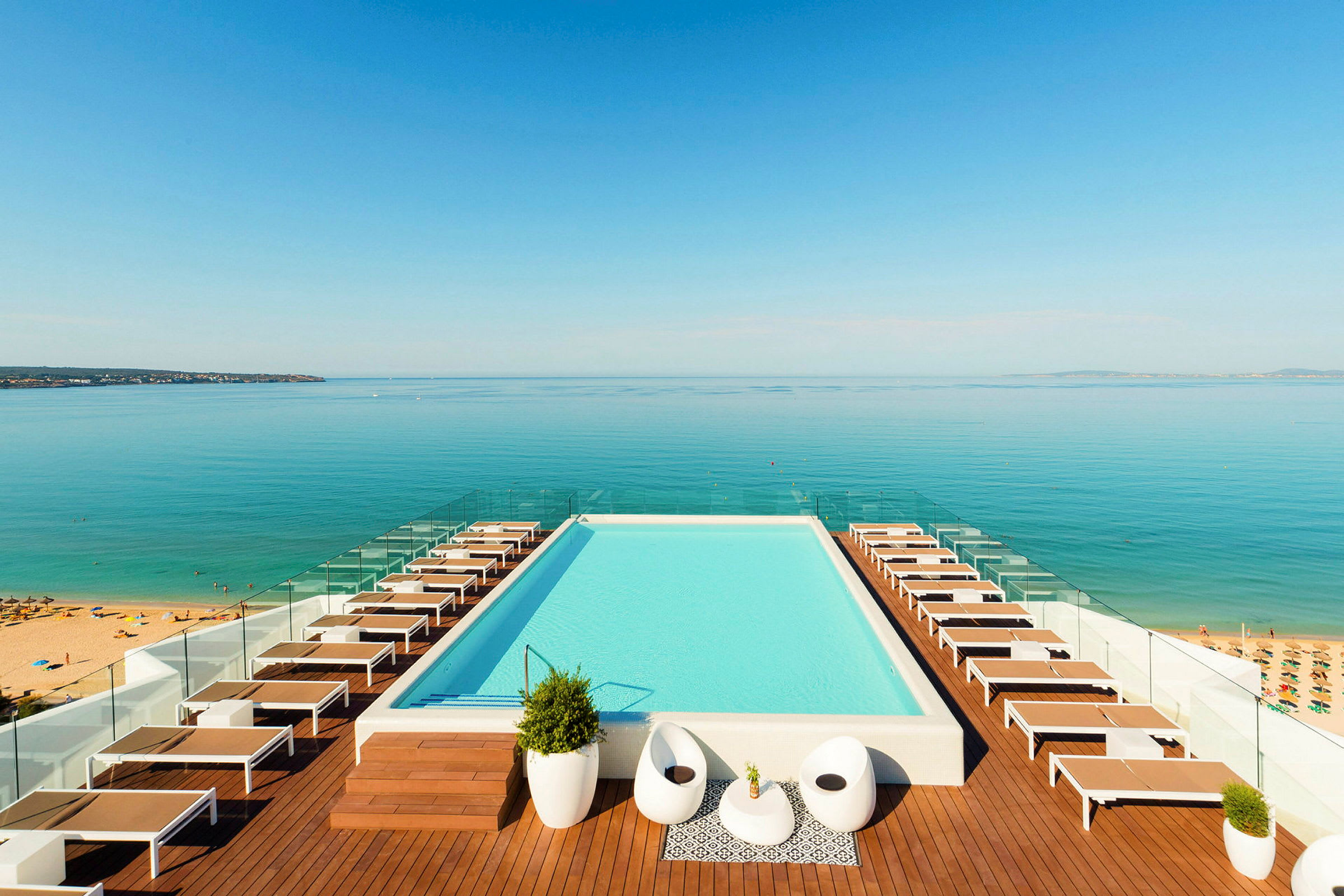En infinitypool med liggestole og udsigt over havet. (AI-genereret tekst)
