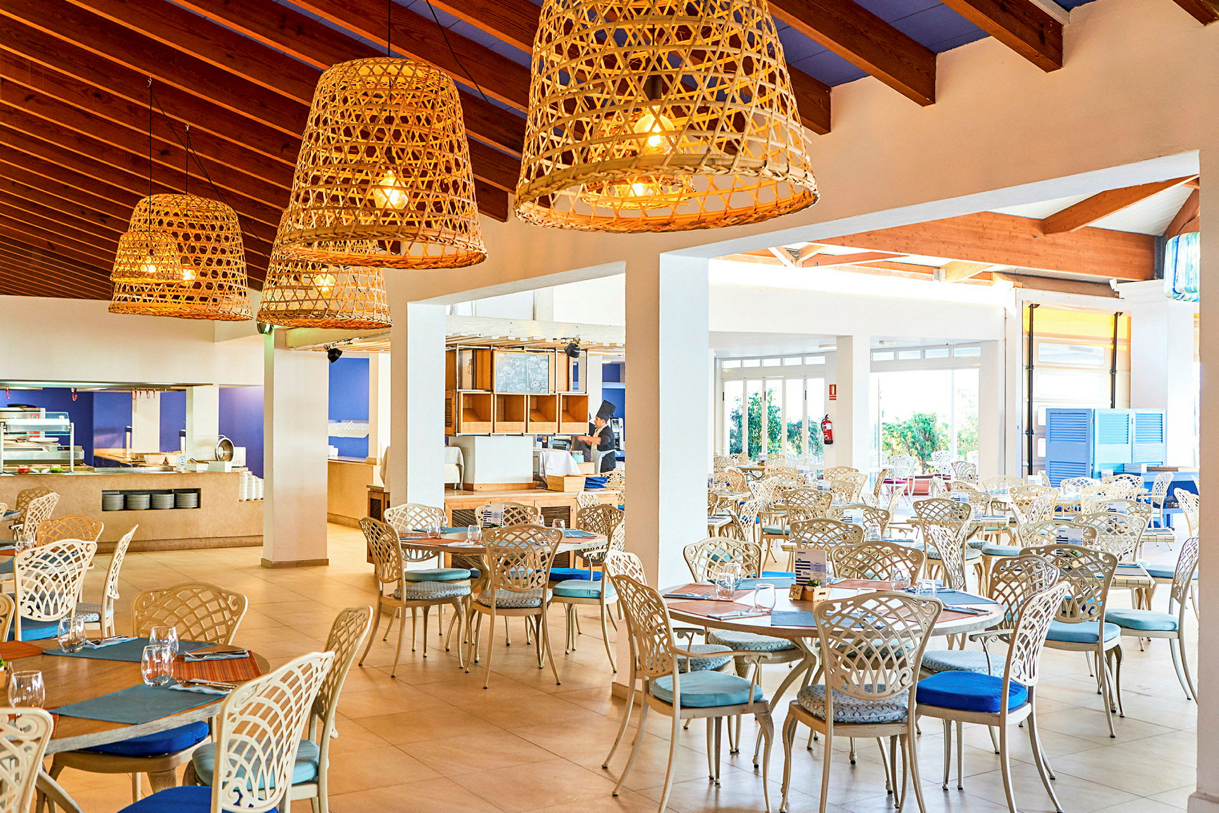 Lys og luftig restaurant med elegant møblement og store kurvelamper. (AI-genereret tekst)