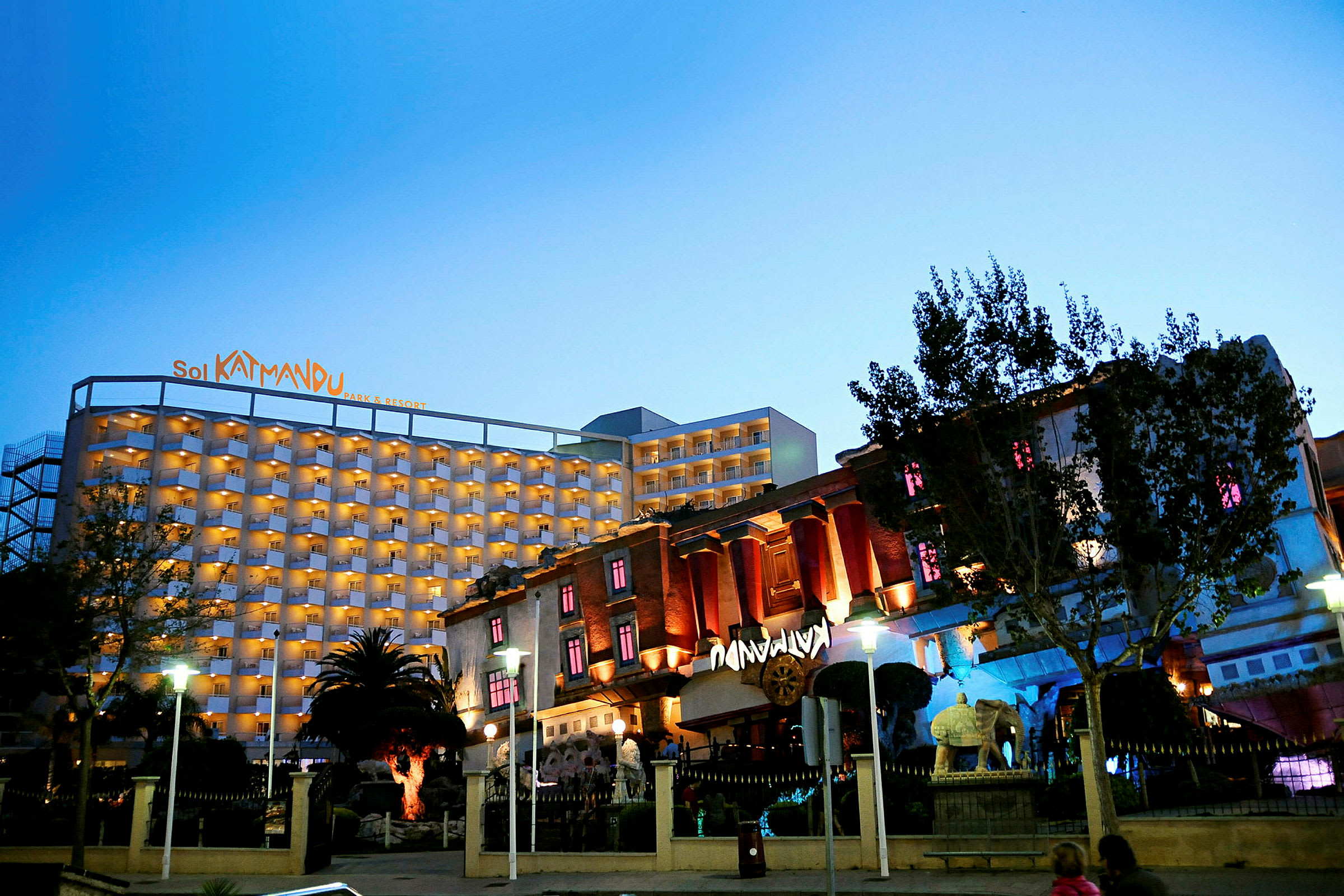 Et hotel kaldet Sol Katmandu Park & Resort, oplyst om aftenen, omgivet af en have. (AI-genereret tekst)