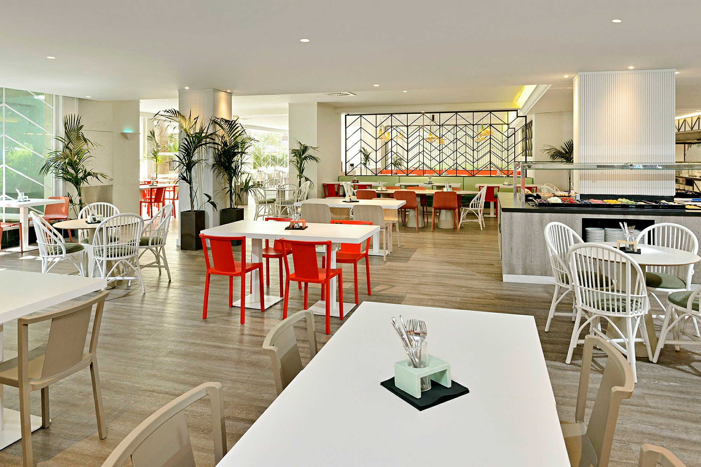 En lys og moderne restaurant med hvide borde og farverige stole. (AI-genereret tekst)