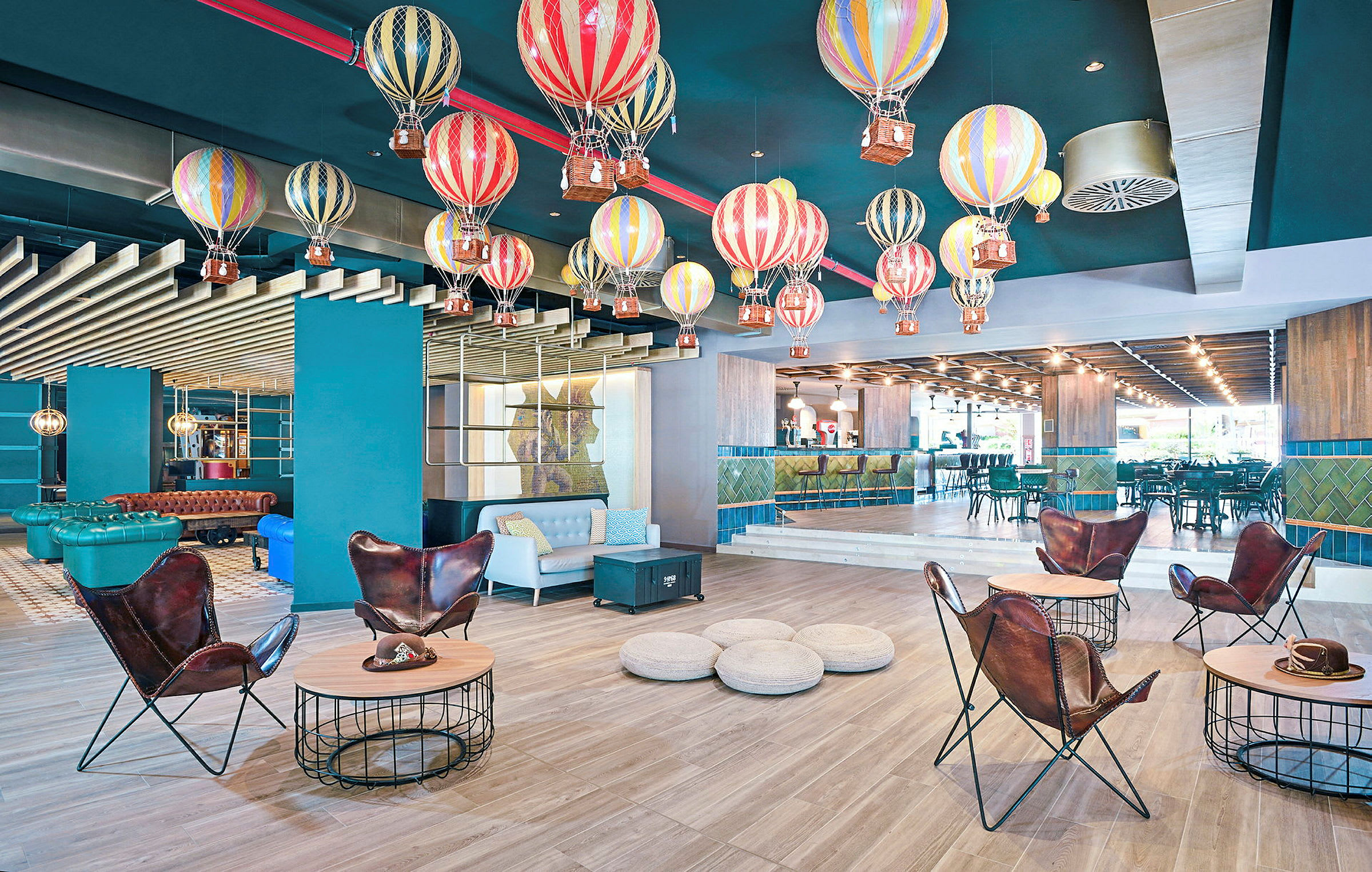 Et rum med farverige luftballoner hængende fra loftet som dekoration, moderne møbler og en bar i baggrunden. (AI-genereret tekst)