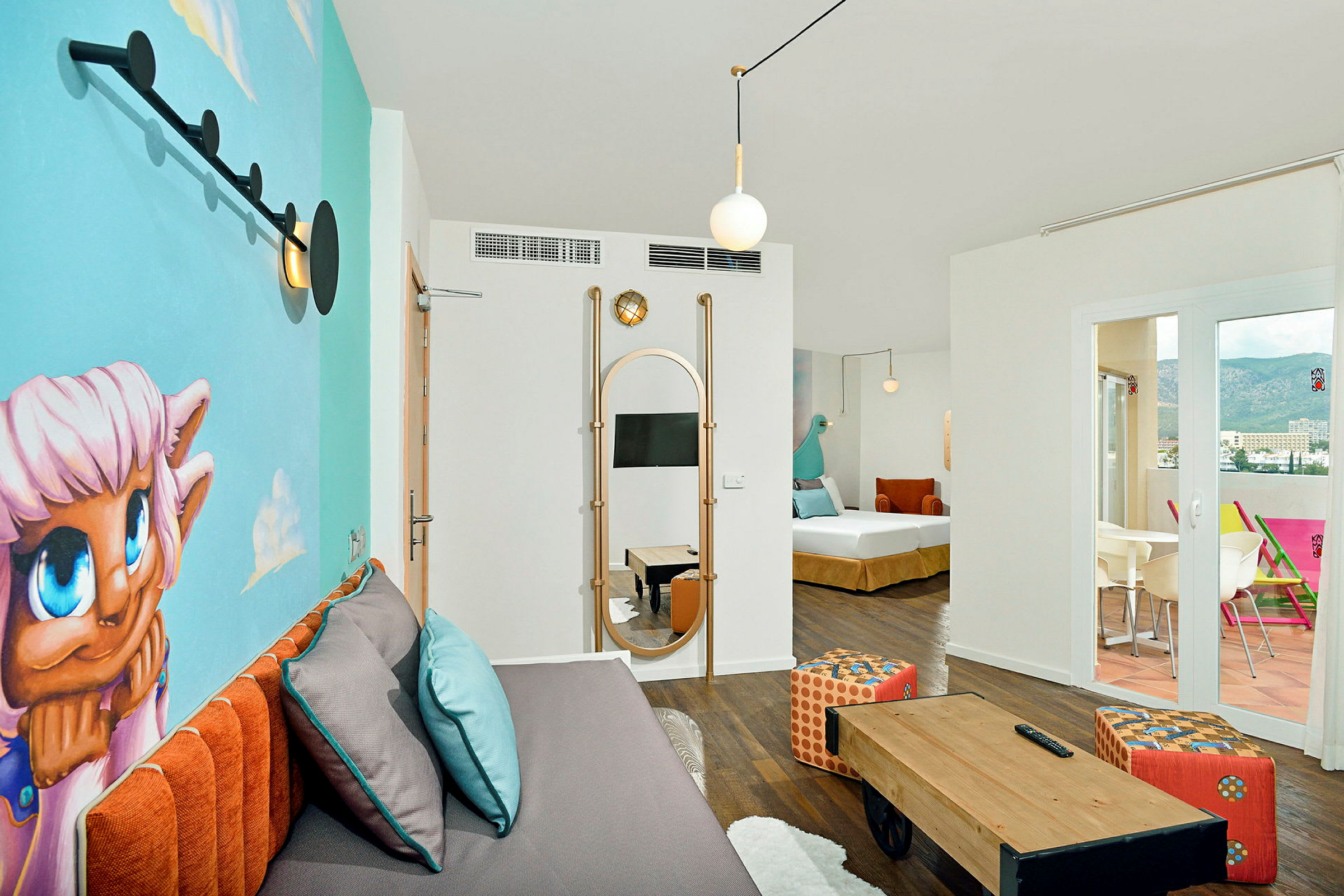Et moderne og farverigt hotelværelse med en vægmaleri, en sofa med puder, et lille bord og en terrasse med udsigt. (AI-genereret tekst)