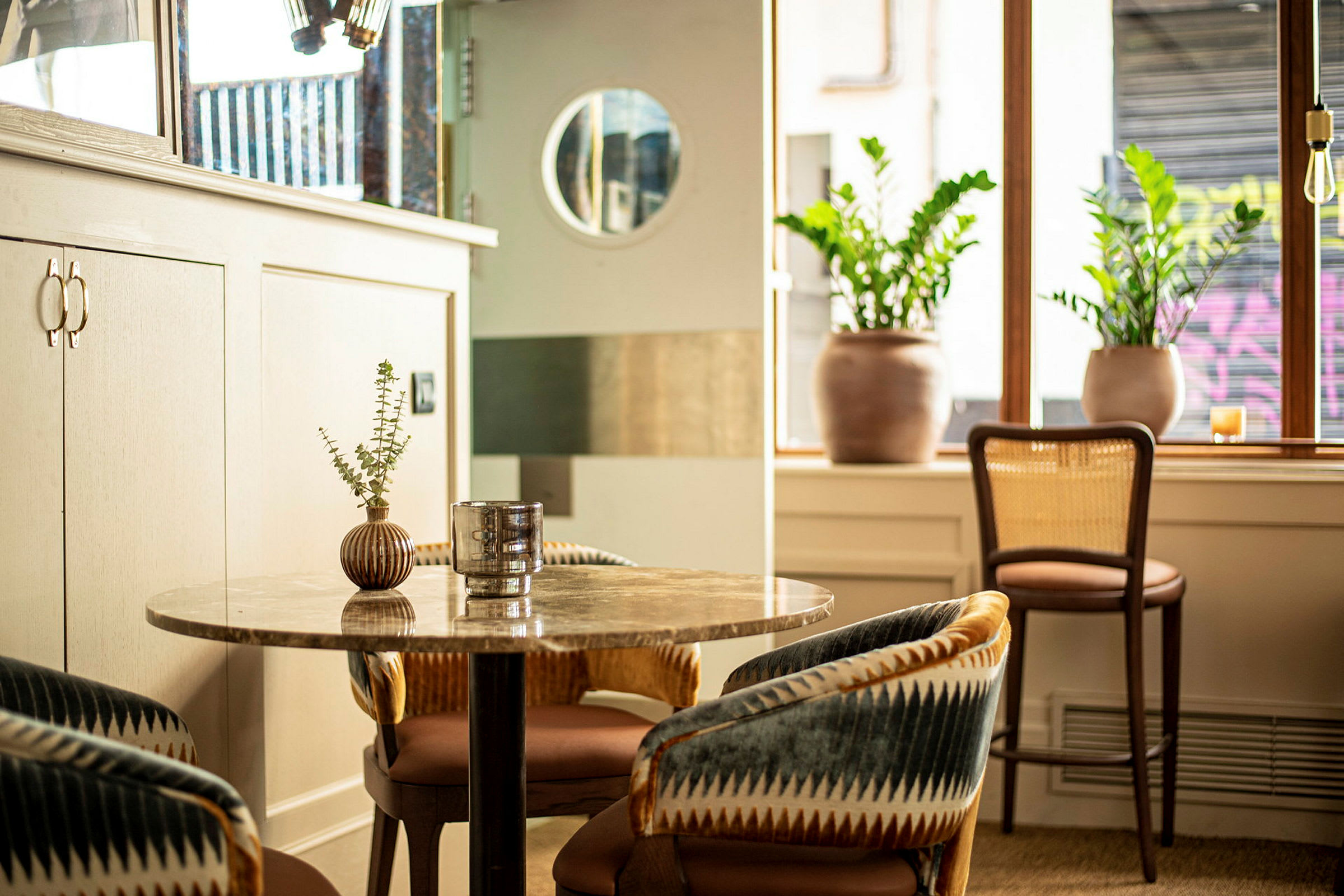 En moderne café med loungestole, et bord og planter. (AI-genereret tekst)