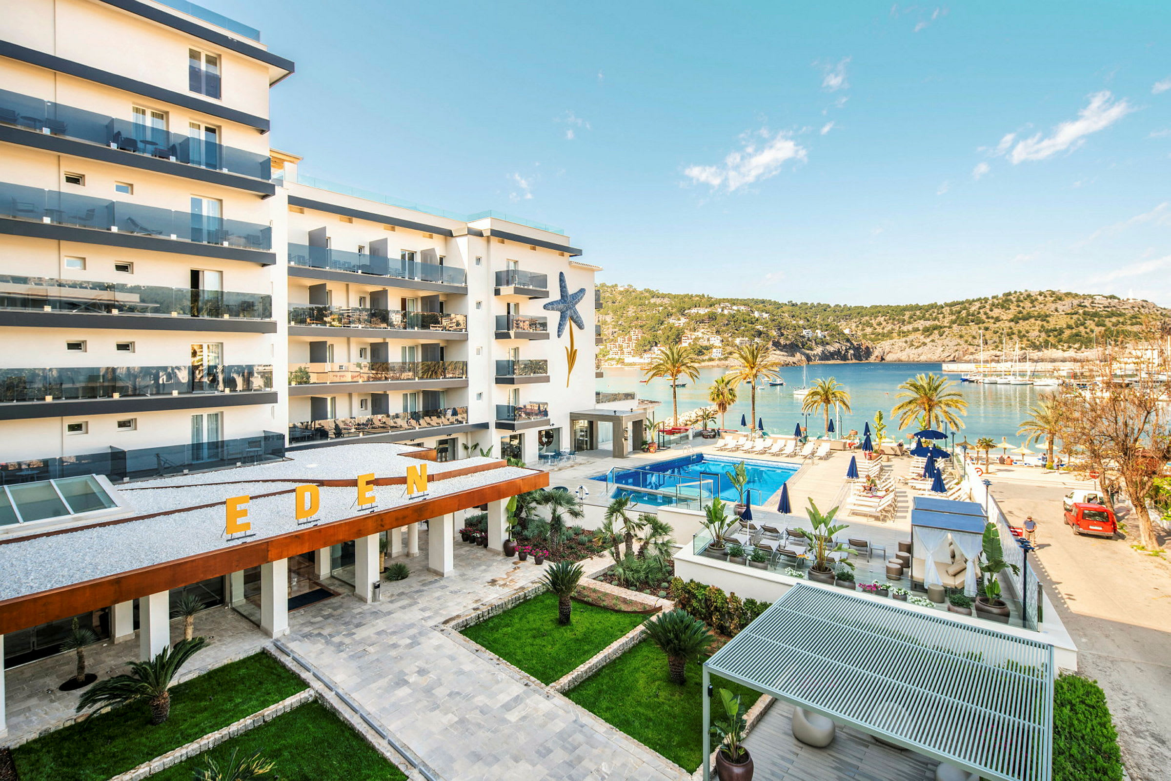 Hotelbygning med altaner og en pool tæt på havet. (AI-genereret tekst)
