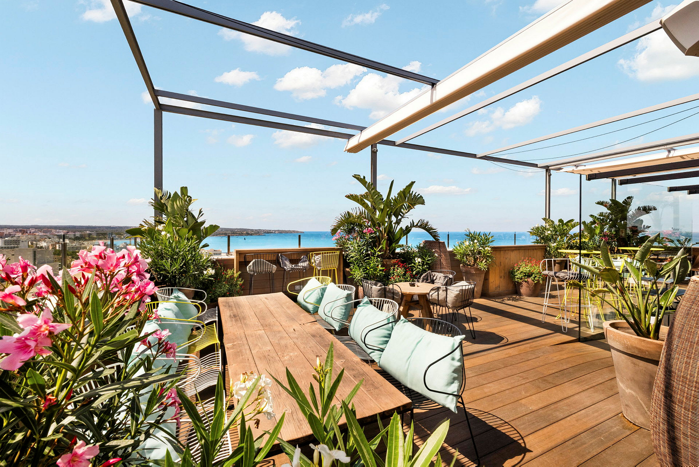 En tagterrasse med siddepladser, grønne planter og udsigt over havet. (AI-genereret tekst)