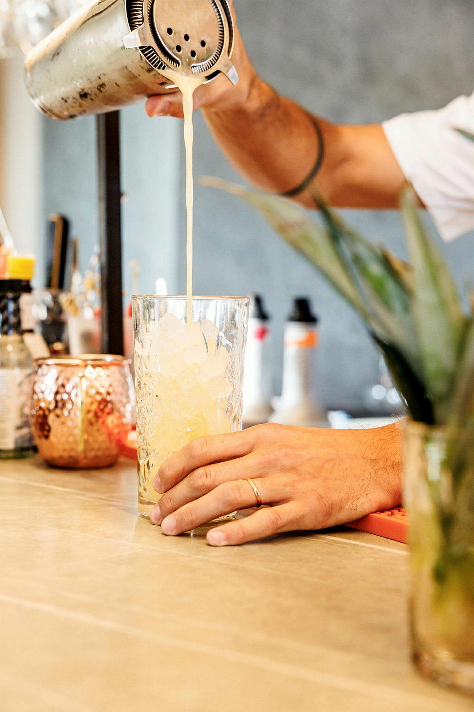 En person hælder en drink fra en shaker ned i et glas fyldt med is. (AI-genereret tekst)