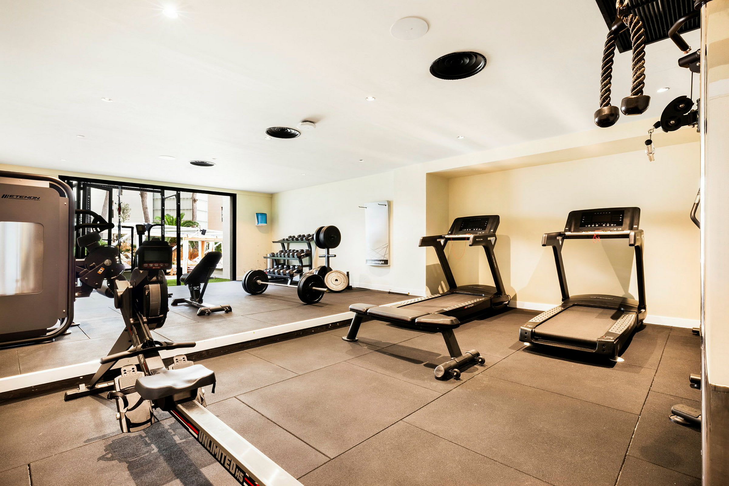 Et fitnesscenter med forskellige træningsudstyr som løbebånd, håndvægte og romaskine. (AI-genereret tekst)