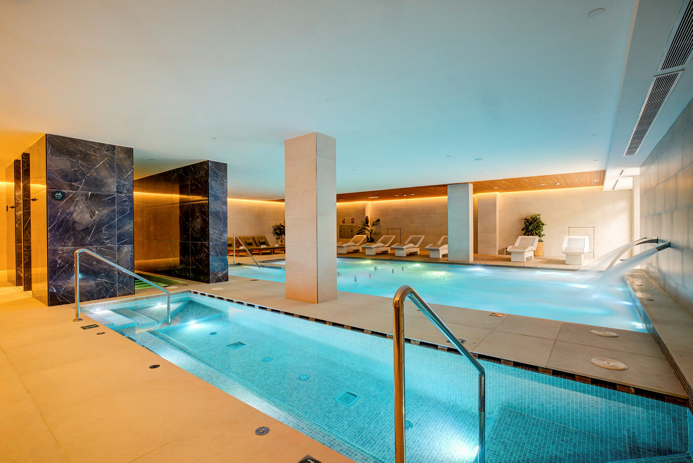 Et moderne spa med en indendørs pool og afslapningsområder. (AI-genereret tekst)