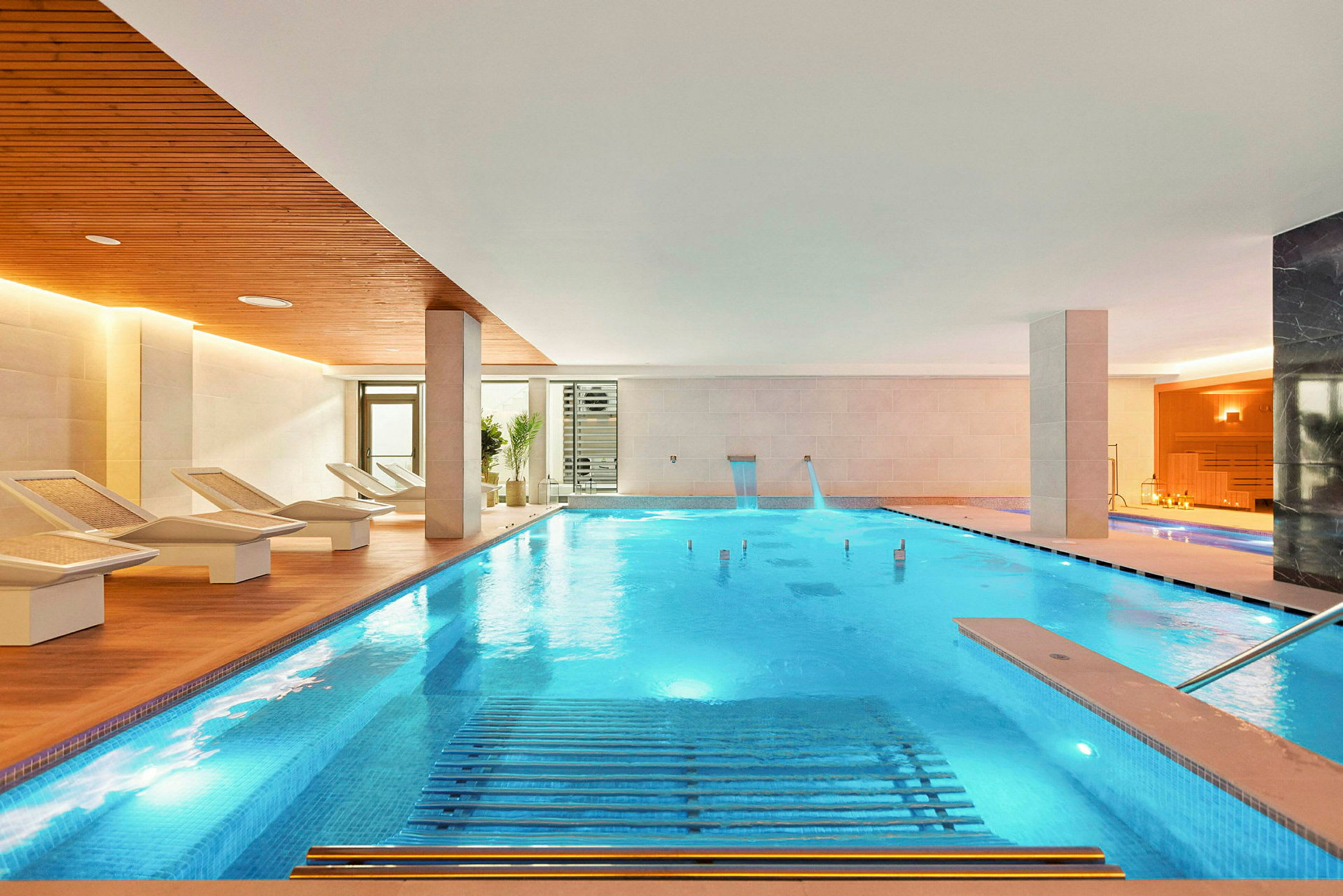 Indendørs pool med trædetaljer og liggestole ved kanten. (AI-genereret tekst)