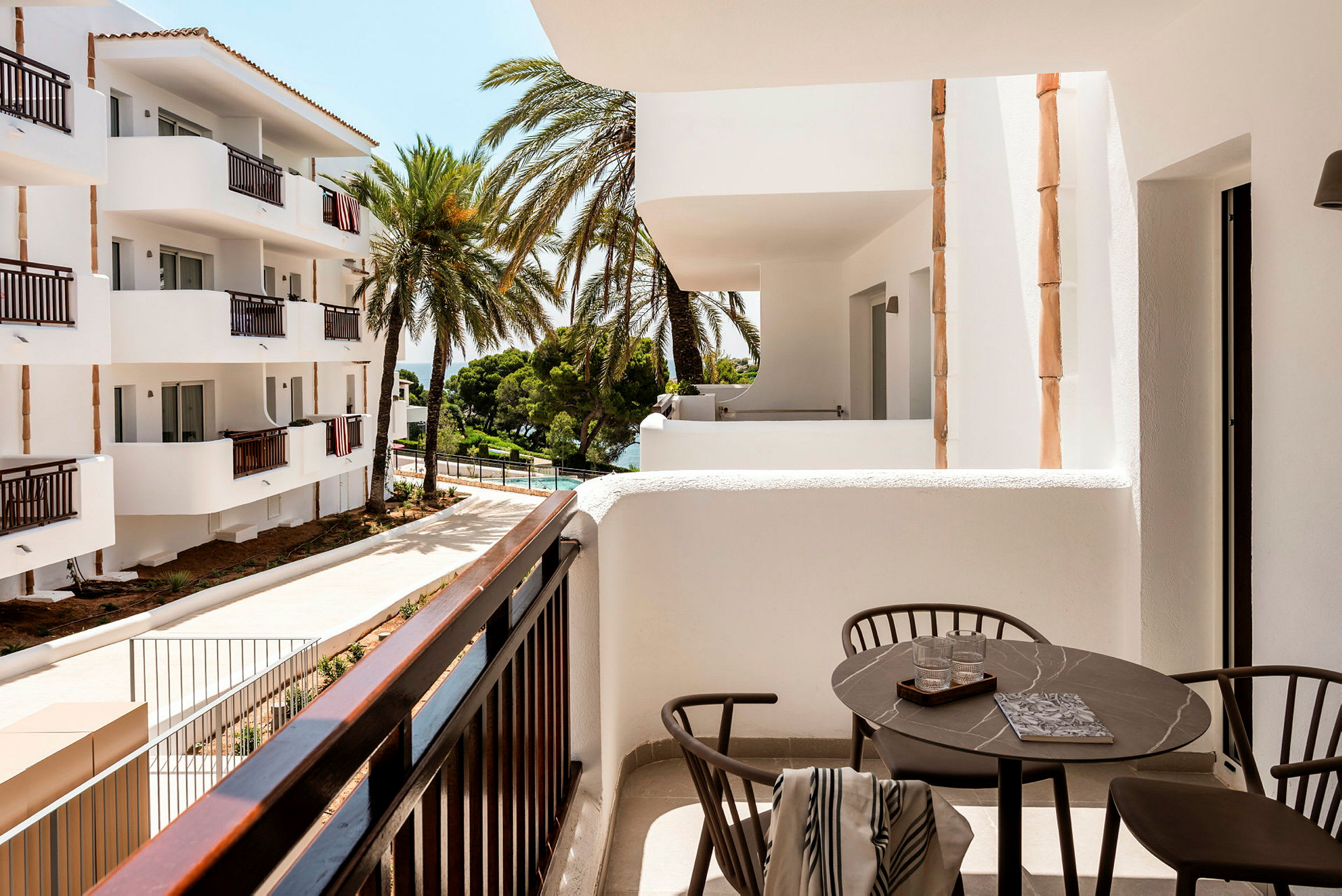 Moderne balkon med udsigt til hvide bygninger og palmer. (AI-genereret tekst)