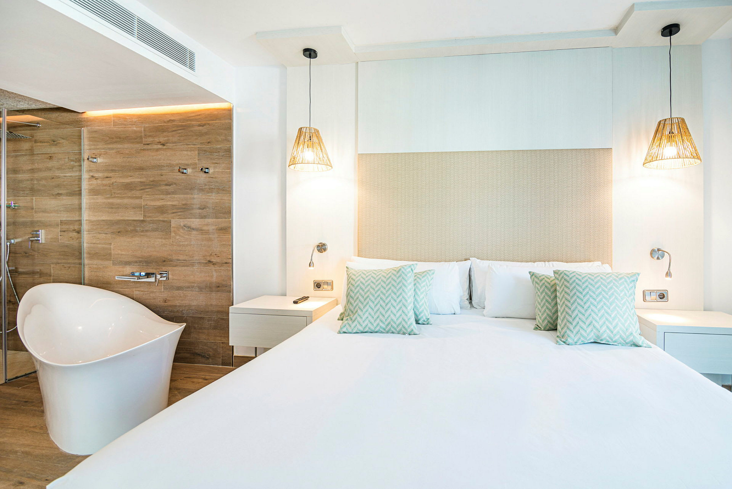 Et moderne hotelværelse med en stor seng, hvide vægge og et fritstående badekar. (AI-genereret tekst)