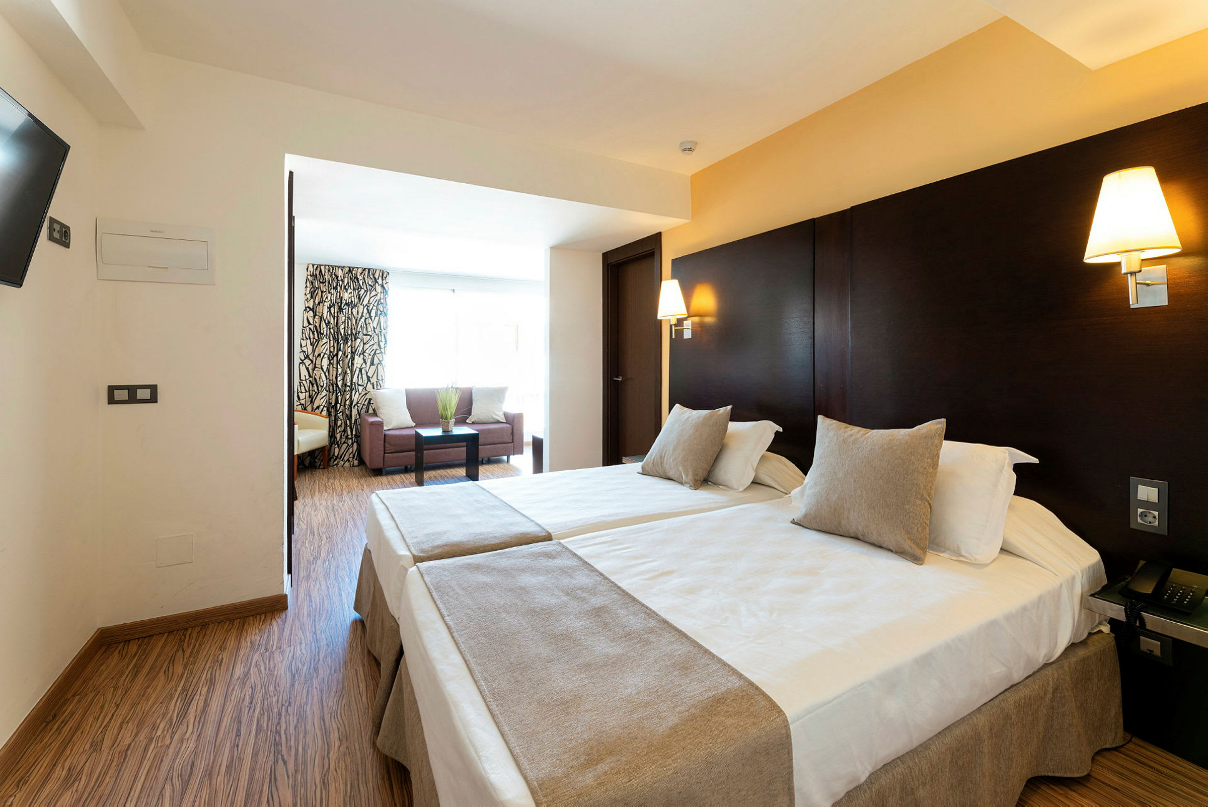 Hotelværelse med to enkeltsenge og et siddeområde. (AI-genereret tekst)