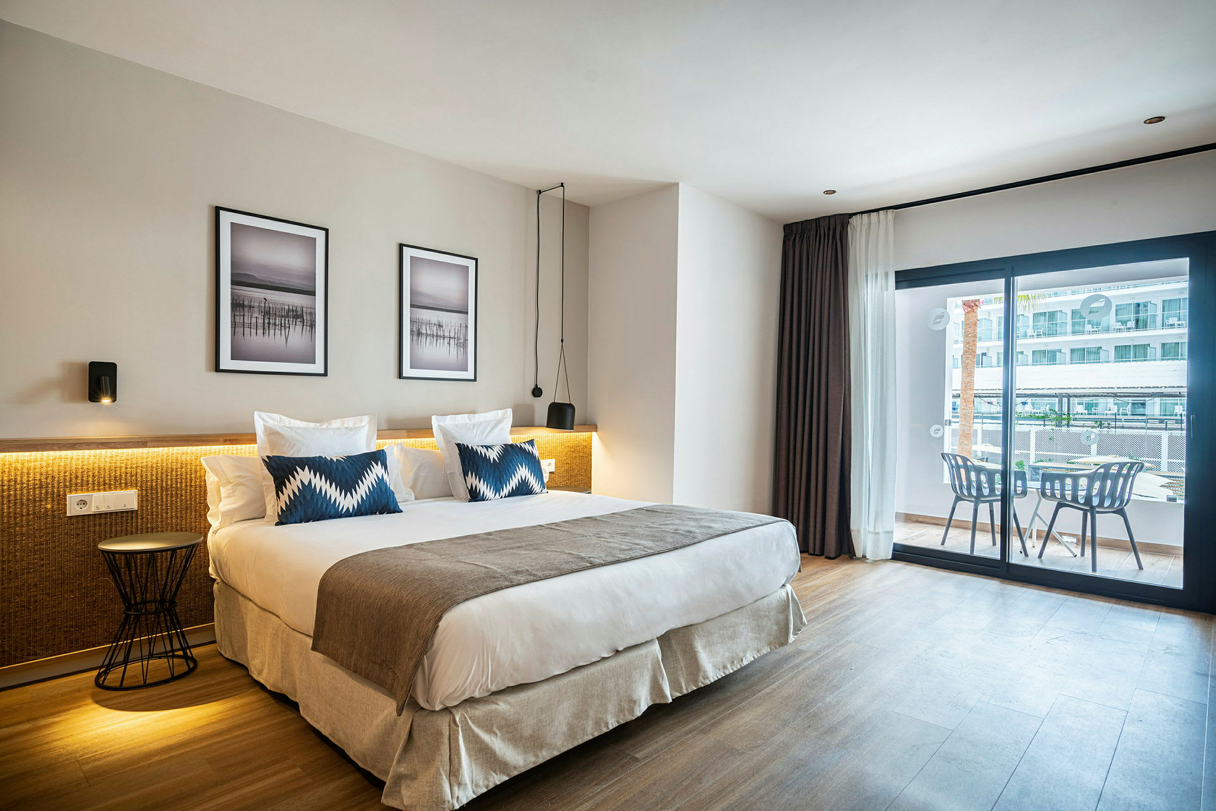 Hotelværelse med en stor seng, to puder og moderne indretning samt en balkon med siddeplads. (AI-genereret tekst)