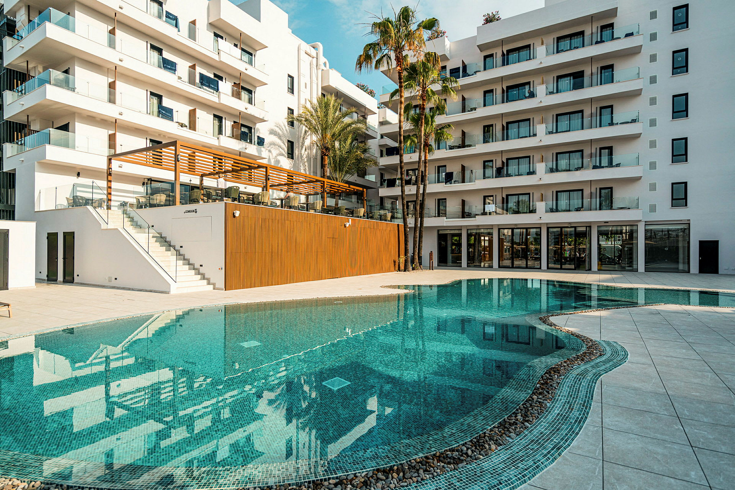 Et moderne hotel med en udendørs pool og palmer i forgrunden. (AI-genereret tekst)