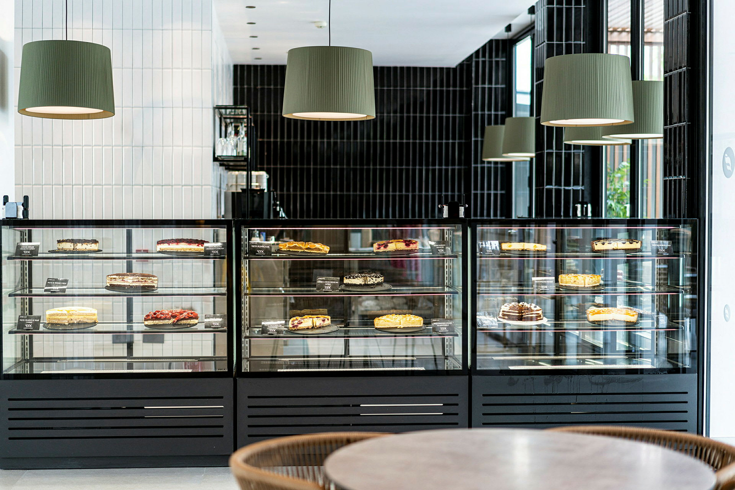 En glasmontrer med forskellige kager, der er udstillet til salg i en moderne café. (AI-genereret tekst)