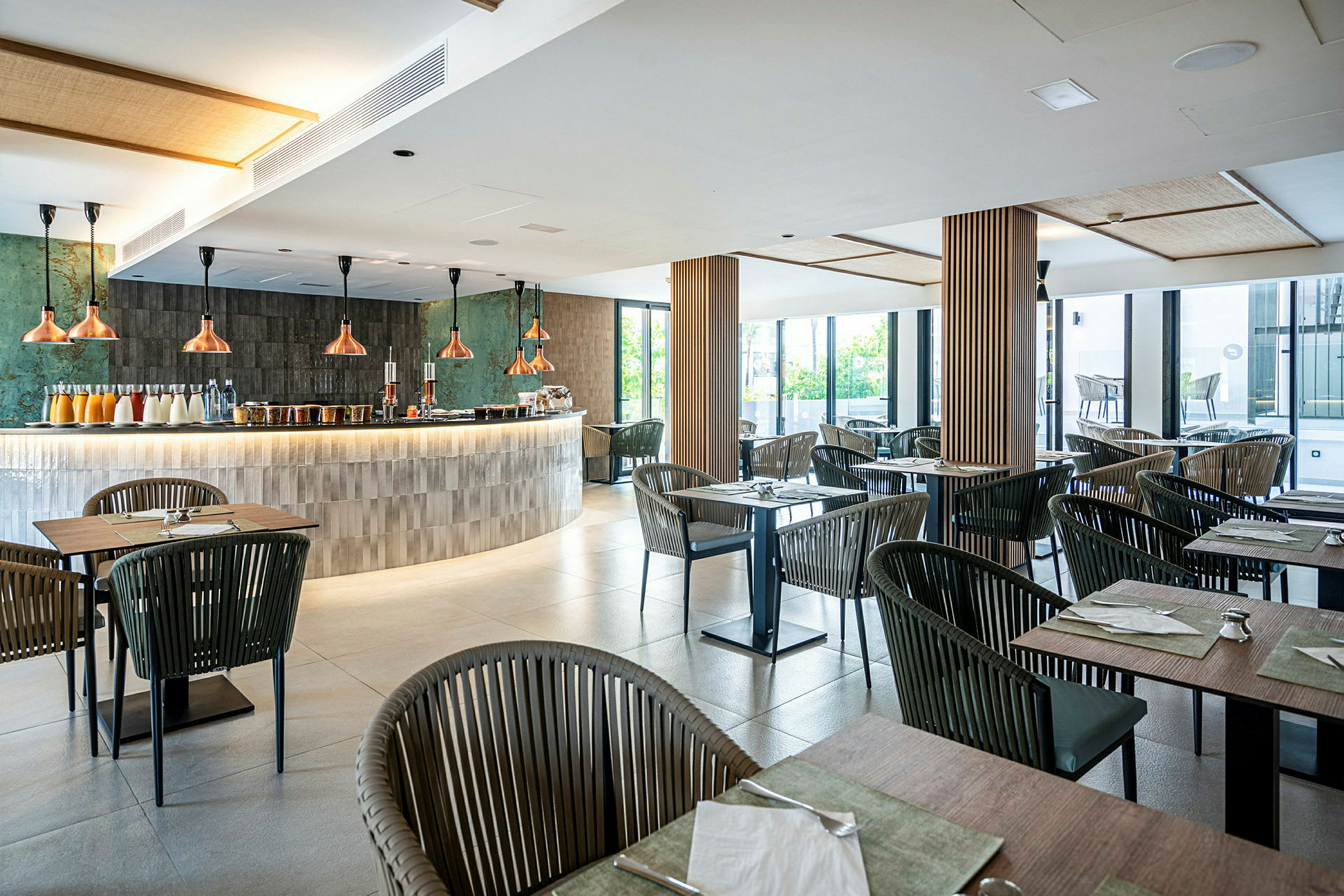 Billede af en moderne restaurant med borde og stole i træ og metal samt en elegant bardisk med kobberlamper. (AI-genereret tekst)
