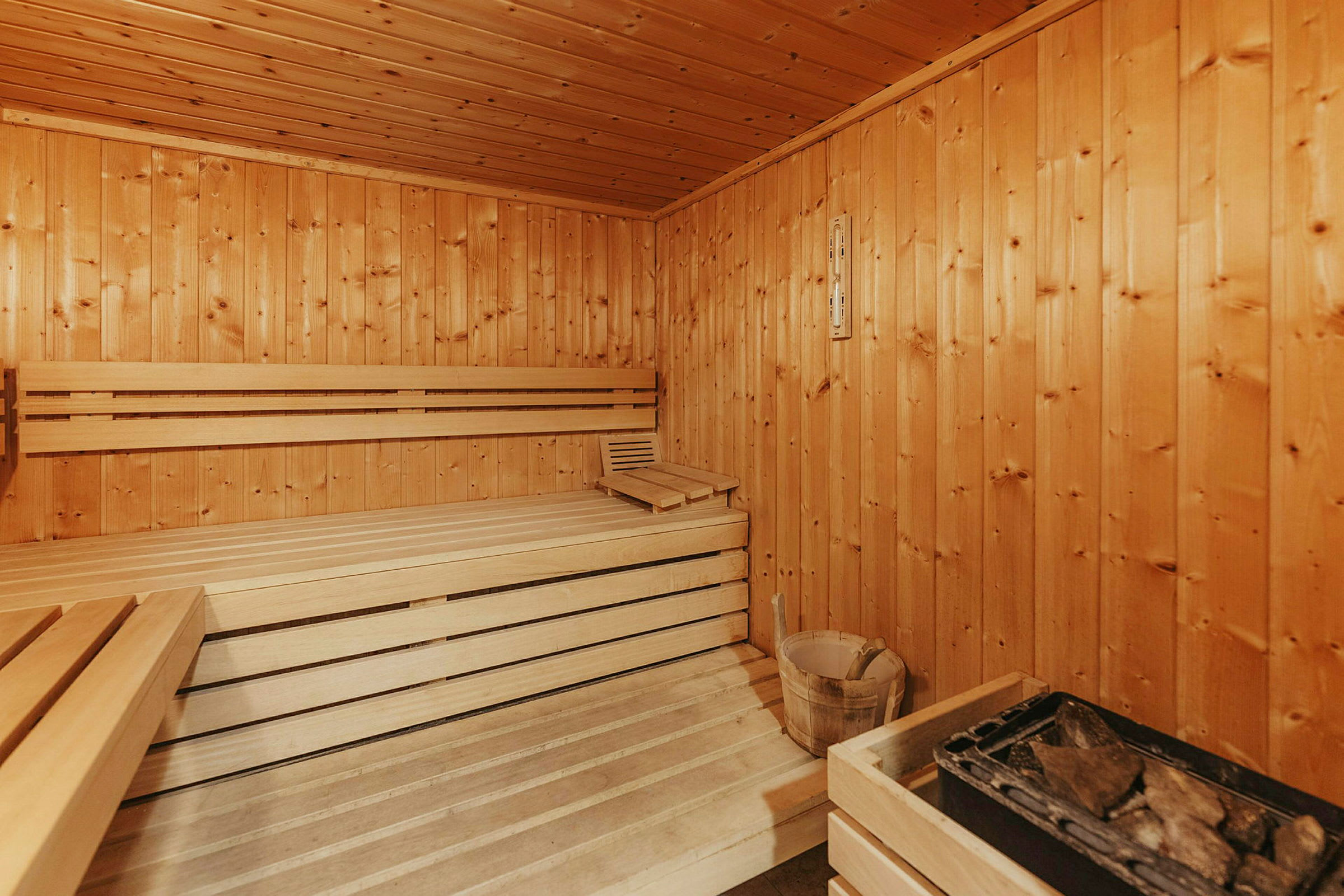 Træbeklædt sauna med siddebænke og sauna sten. (AI-genereret tekst)