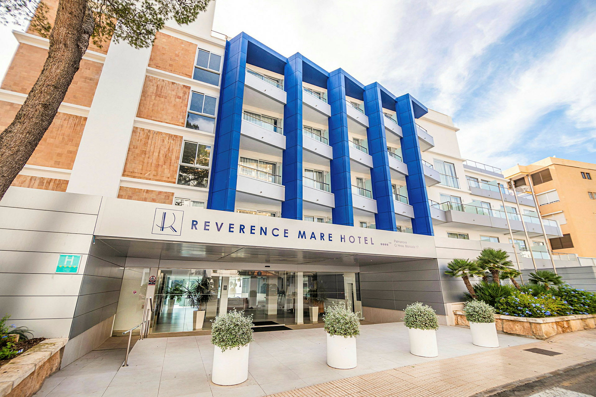 Hotelbygning med skiltet "Reverence Mare Hotel". Facade med blå detaljer og glasaltaner. (AI-genereret tekst)