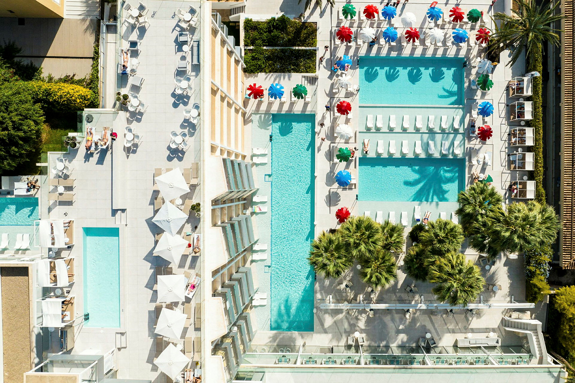 Luftfoto af et resort med poolområder, liggestole og parasoller. (AI-genereret tekst)