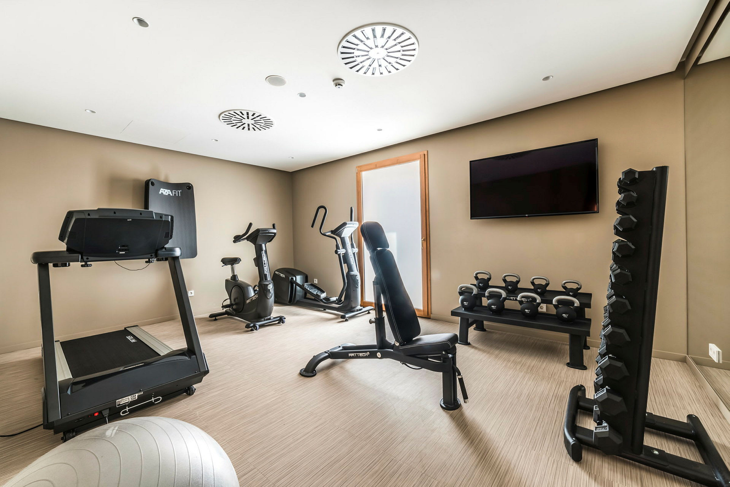 Et fitnessrum med træningsmaskiner, håndvægte og kettlebells. (AI-genereret tekst)