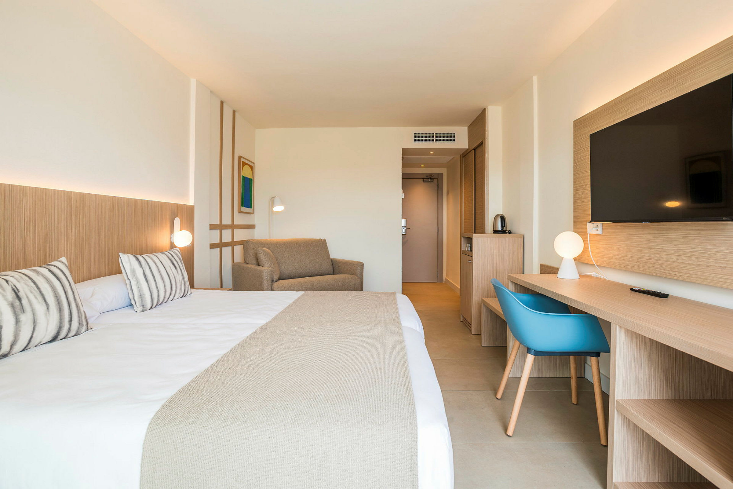 Hotelværelse med dobbeltseng, sofa, skrivebord og TV. (AI-genereret tekst)