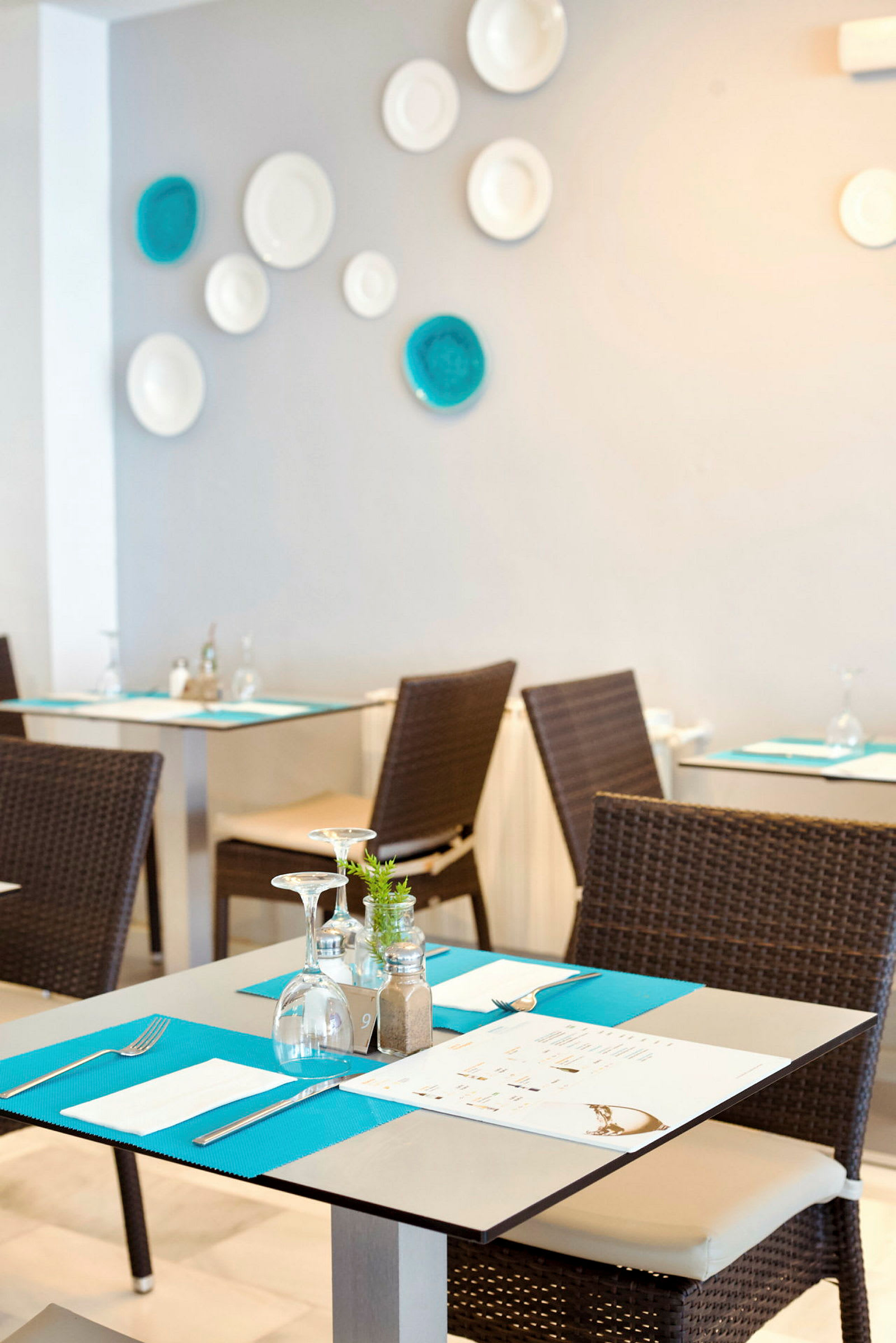 En restaurant med dækkede borde og stole, med dekorationer på væggen. (AI-genereret tekst)