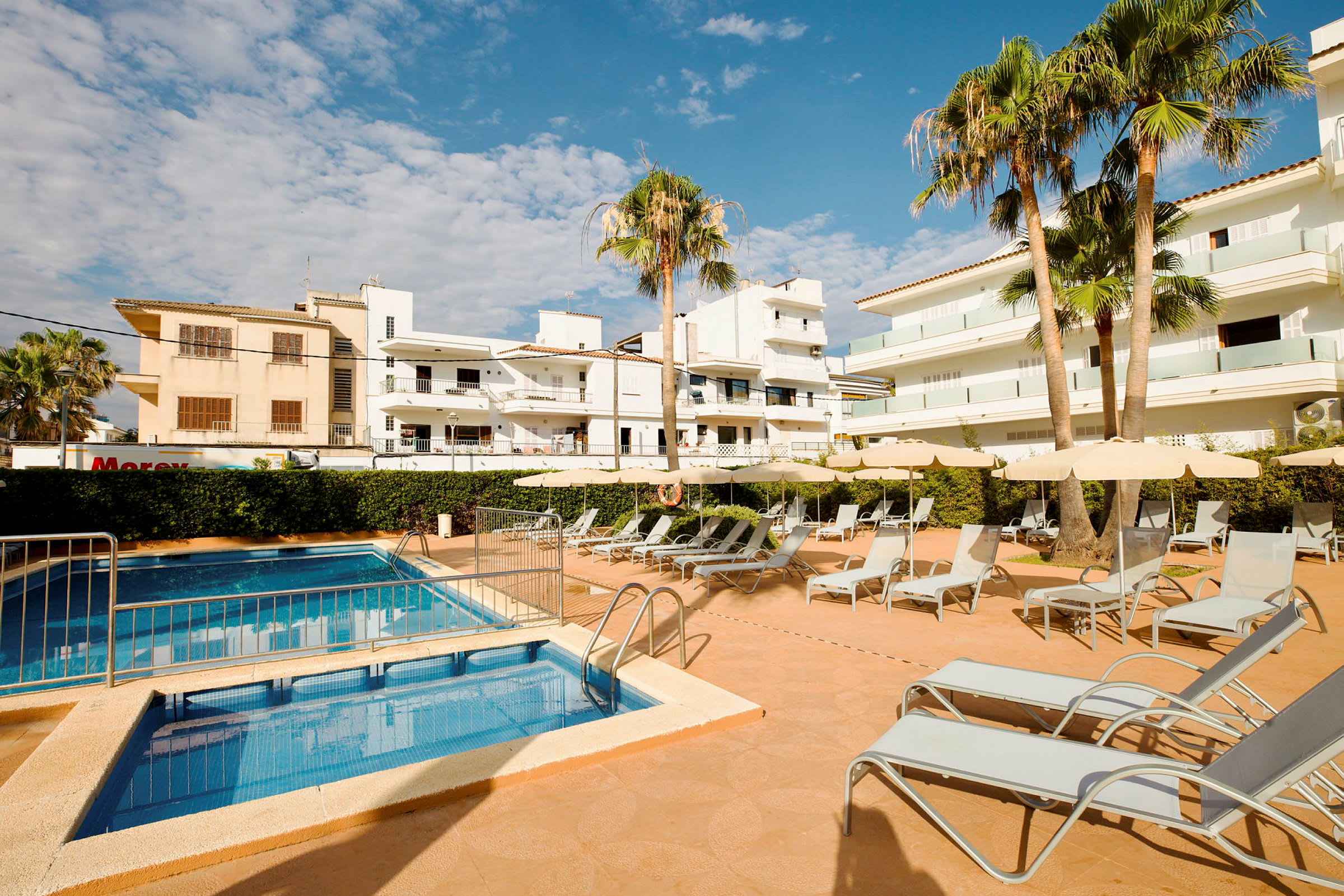 En hotelpool med liggestole og parasoller på solterrassen. (AI-genereret tekst)