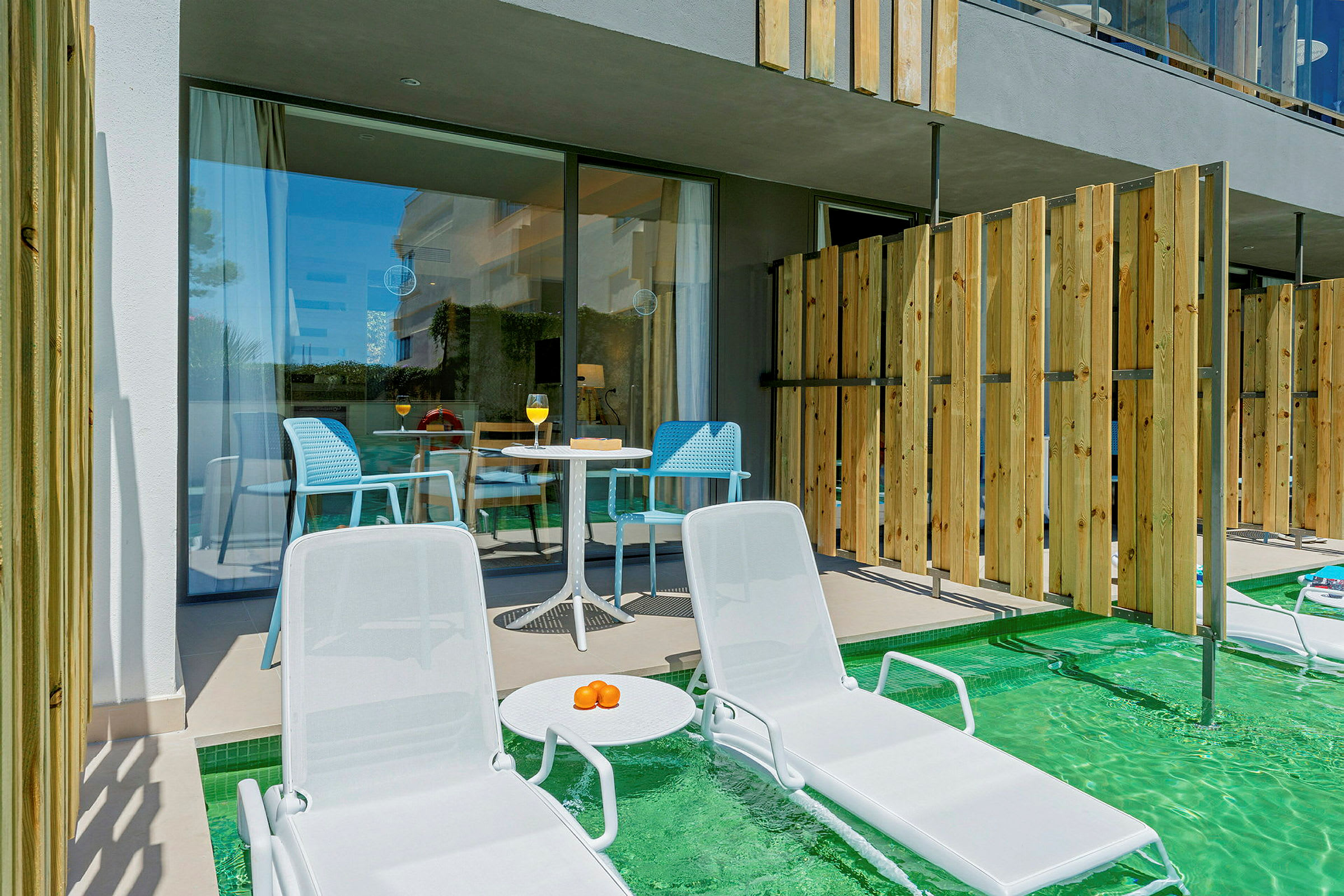To liggestole ved en pool med en terrasse og bord i baggrunden. (AI-genereret tekst)