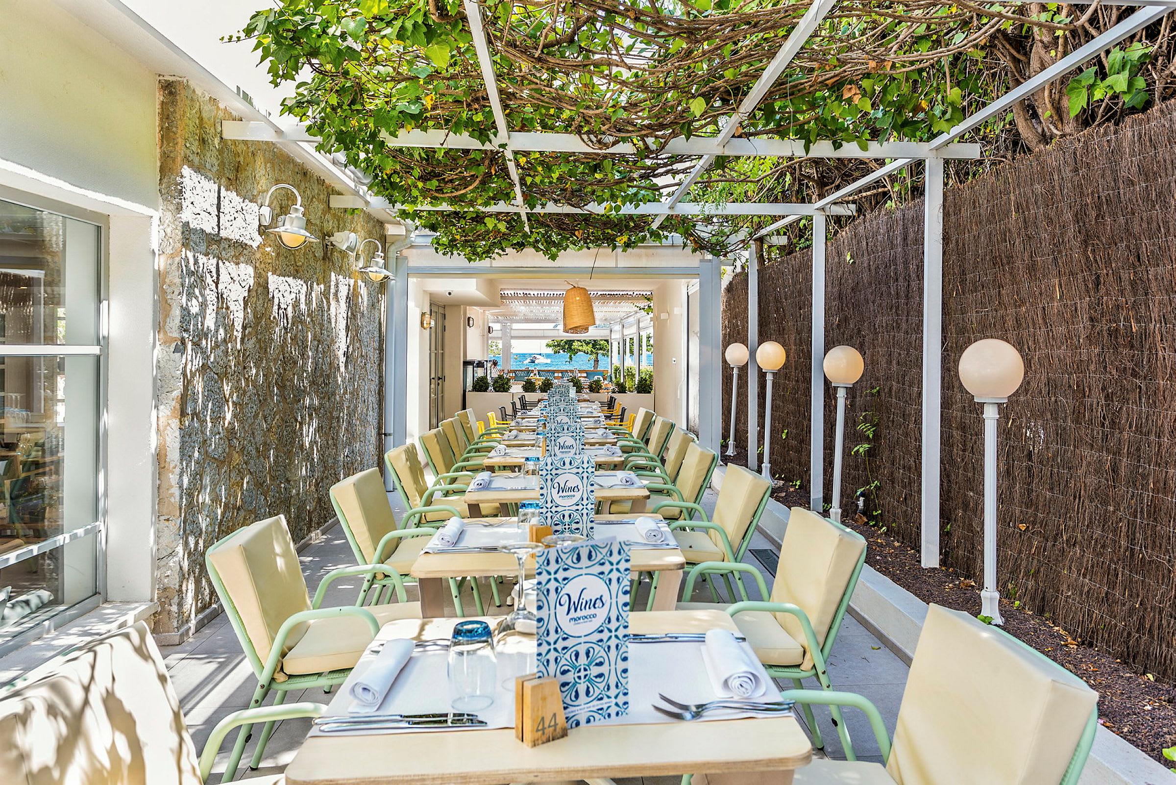 En udendørsrestaurant med siddepladser under en pergola. (AI-genereret tekst)
