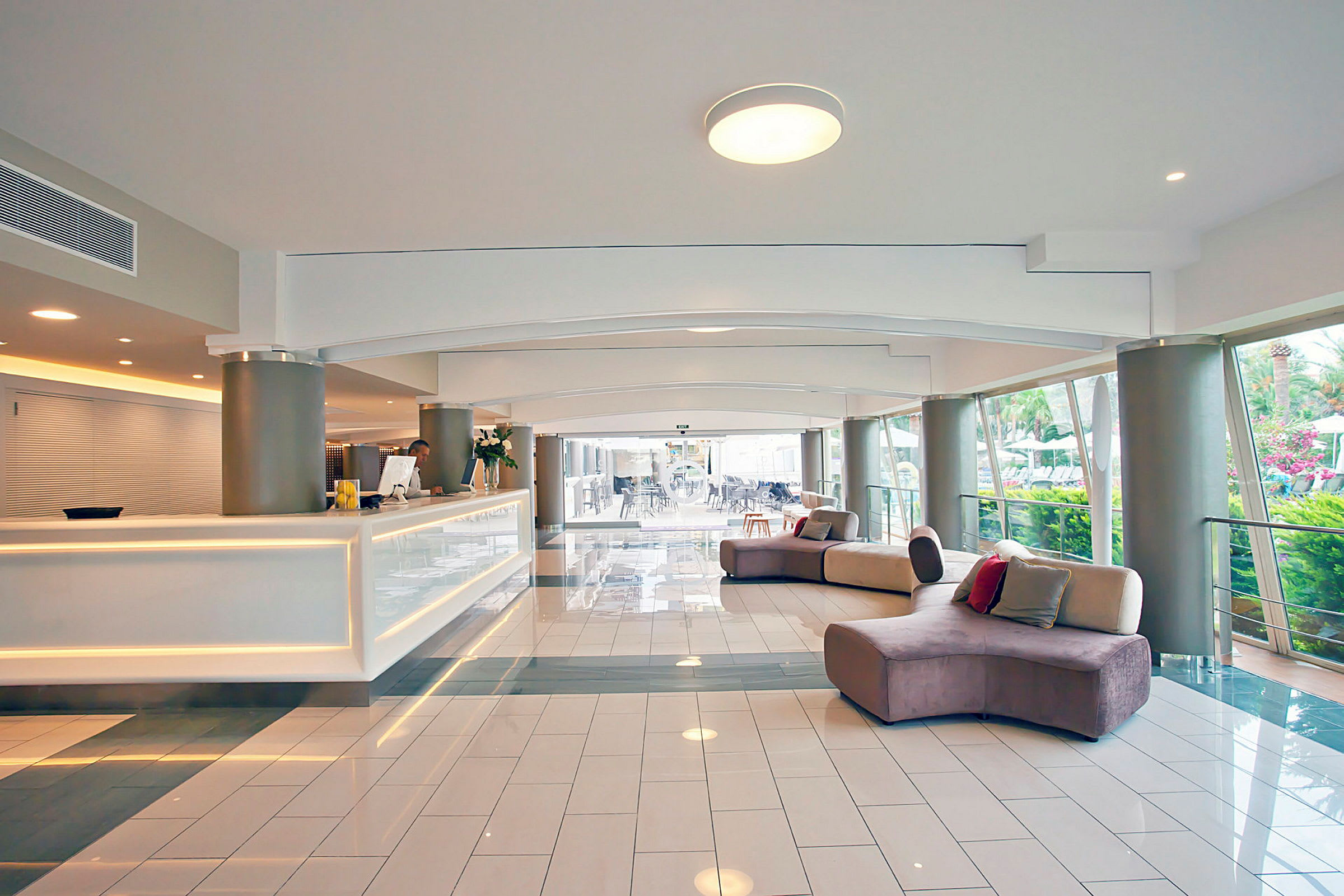 Hotelreception med hvid skranke og sofaer i et moderne og lyst rum. (AI-genereret tekst)