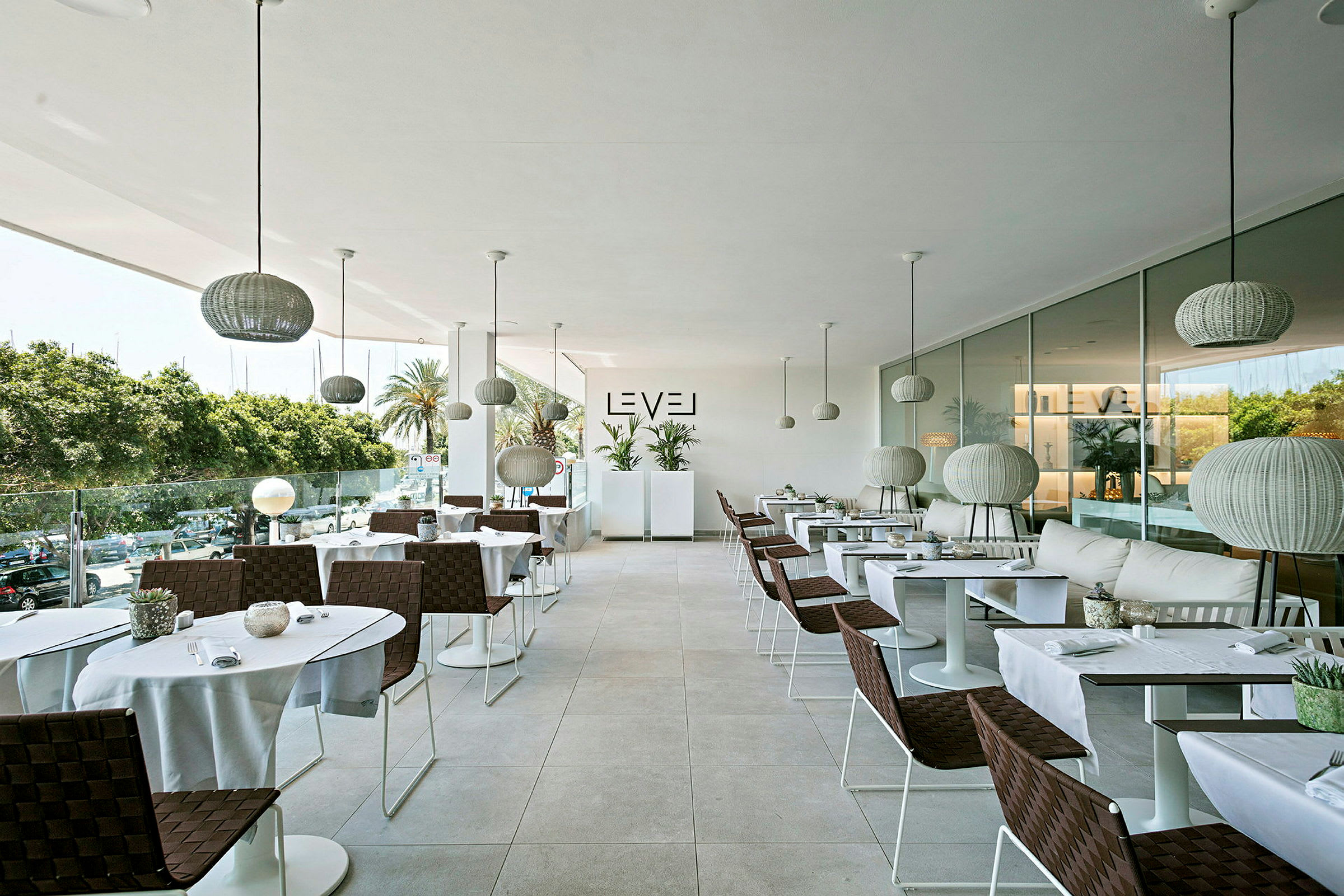 En moderne restaurant med elegante borde og stole, store glasvinduer og hængende lamper. (AI-genereret tekst)