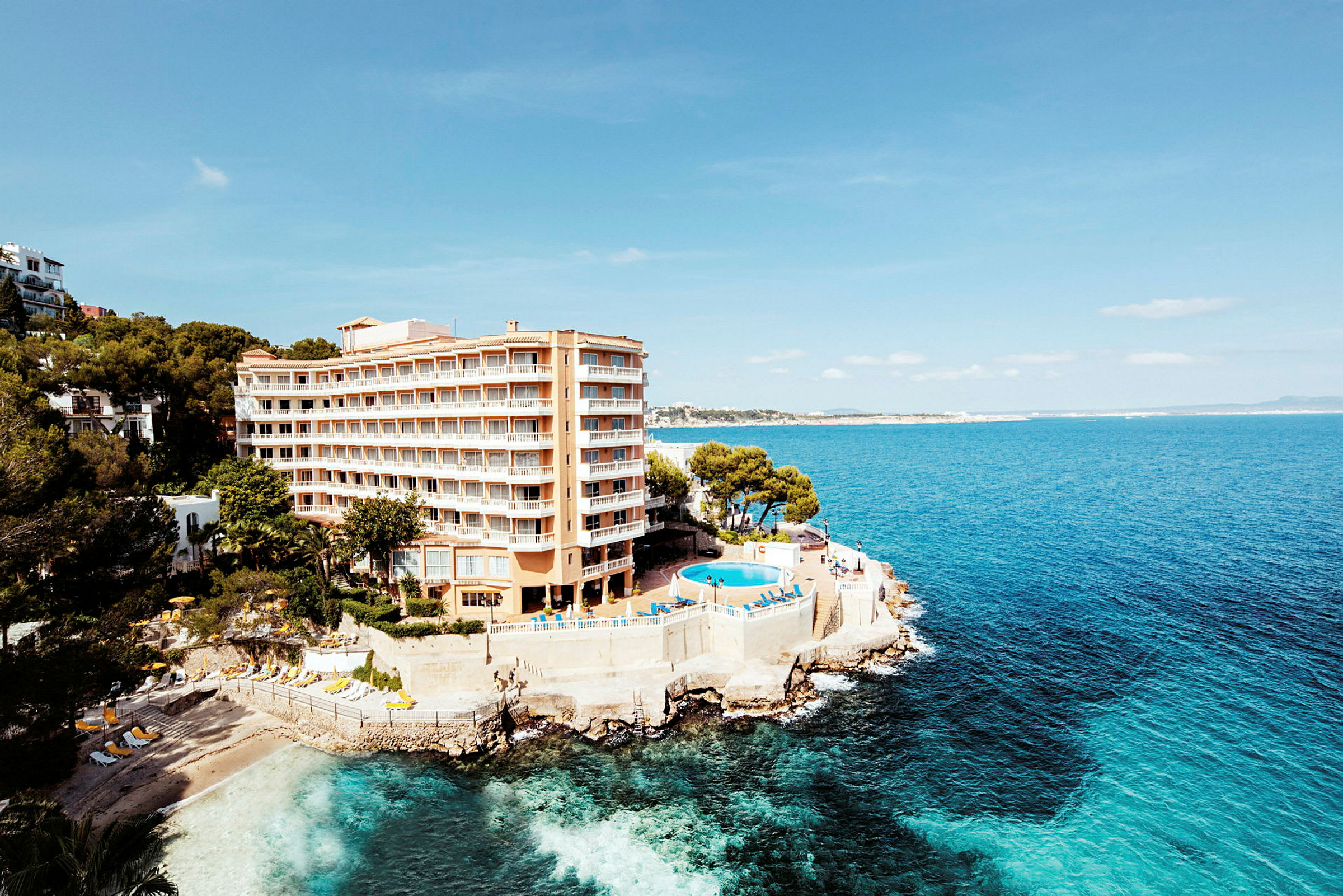 Hotel ved kysten med en pool og udsigt over havet. (AI-genereret tekst)
