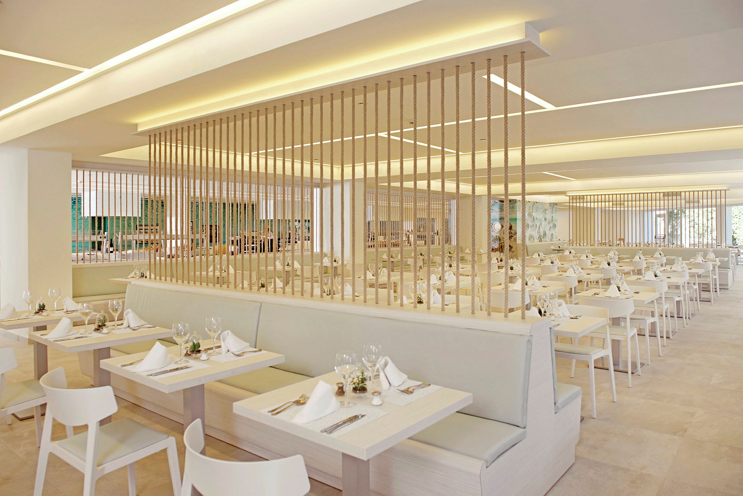 En moderne og lys restaurant med opdækkede borde på række og dekorative reb, der adskiller sektionerne. (AI-genereret tekst)