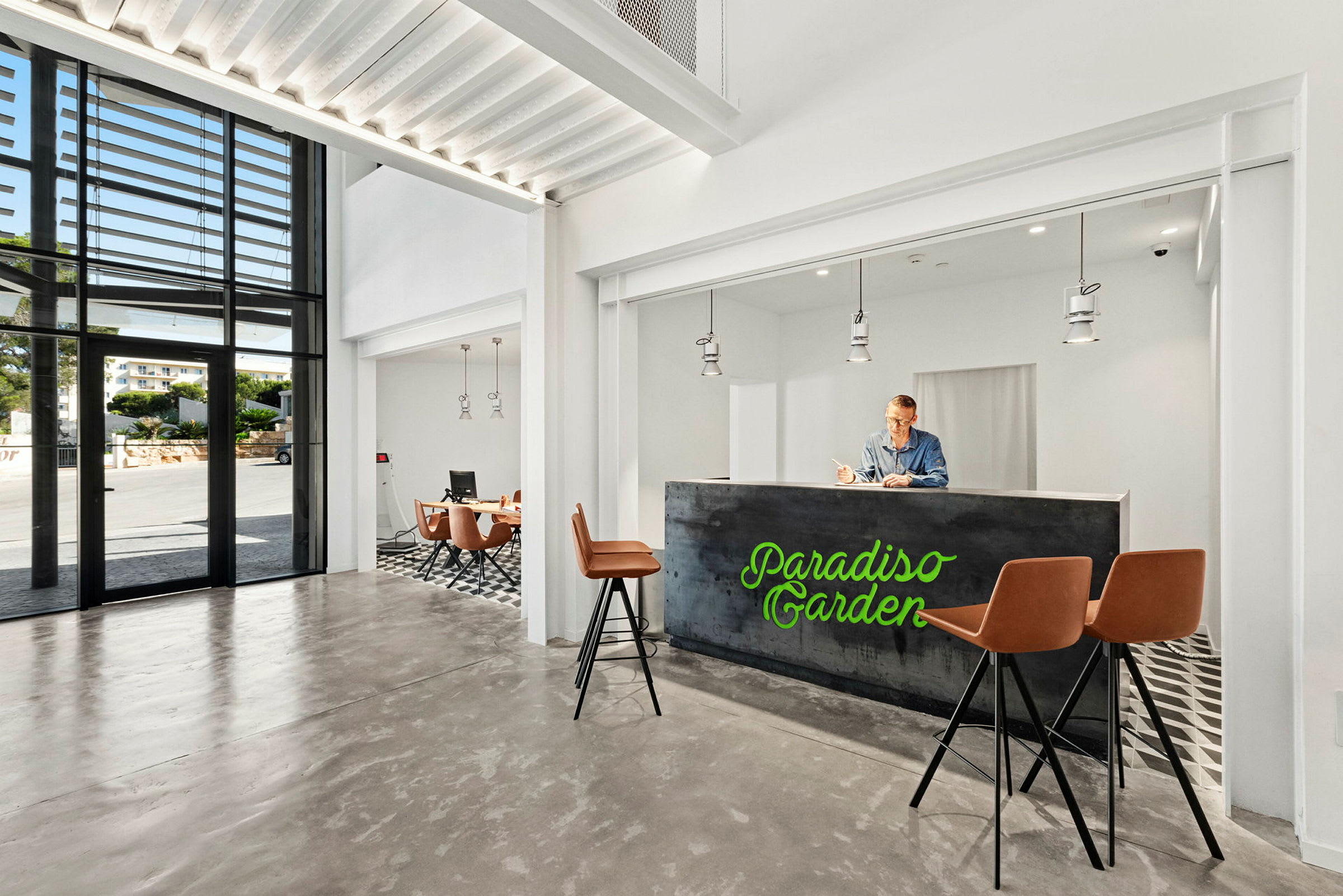 Et moderne hotel-lobbyområde med receptionsskranke, barstole og et siddeområde i et lyst og luftigt miljø. (AI-genereret tekst)