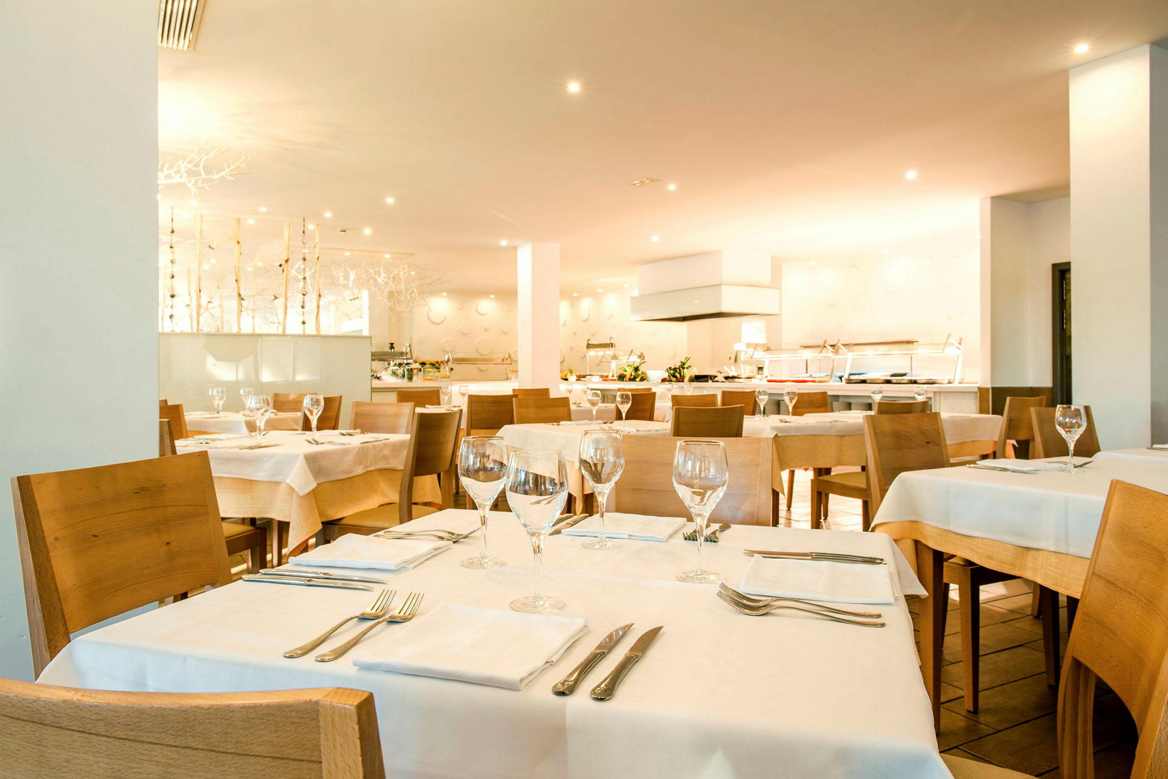 Et restaurantinteriør med flere dækkede borde og træstole. (AI-genereret tekst)