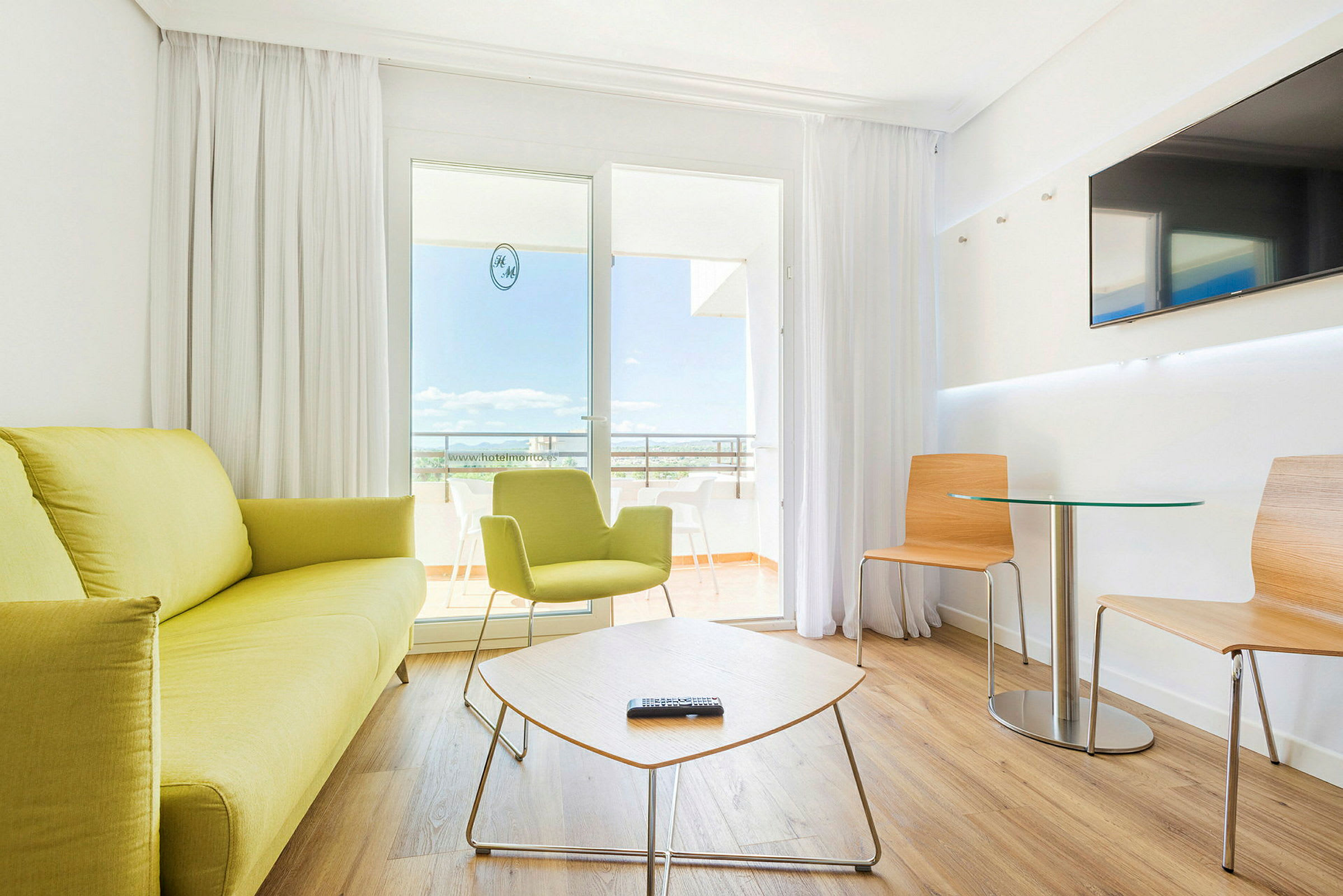 Et moderne hotelværelse med lyse møbler og siddegruppe. (AI-genereret tekst)