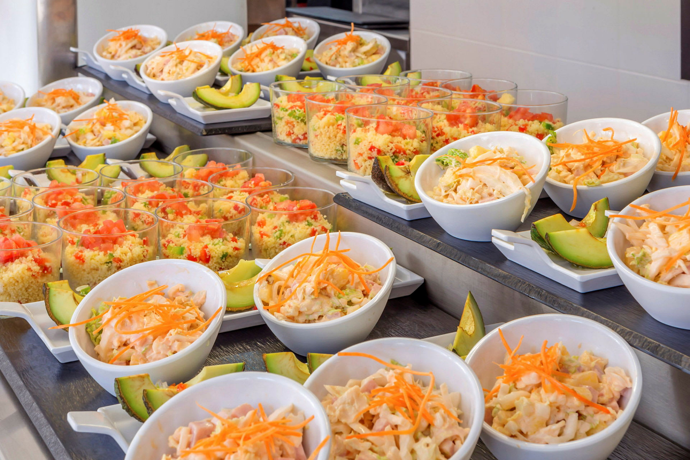Buffet med små skåle med salat og avocado samt glas med farverige couscous-retter. (AI-genereret tekst)