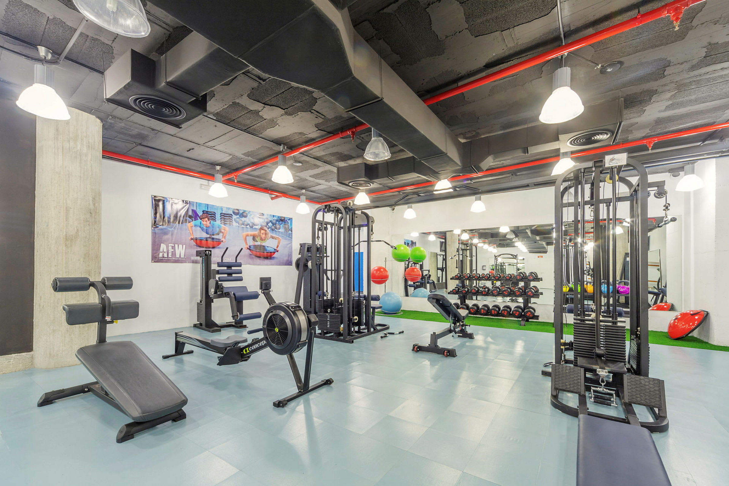 Interiør af et moderne fitnesscenter med forskellige træningsmaskiner og styrketræningsudstyr. (AI-genereret tekst)