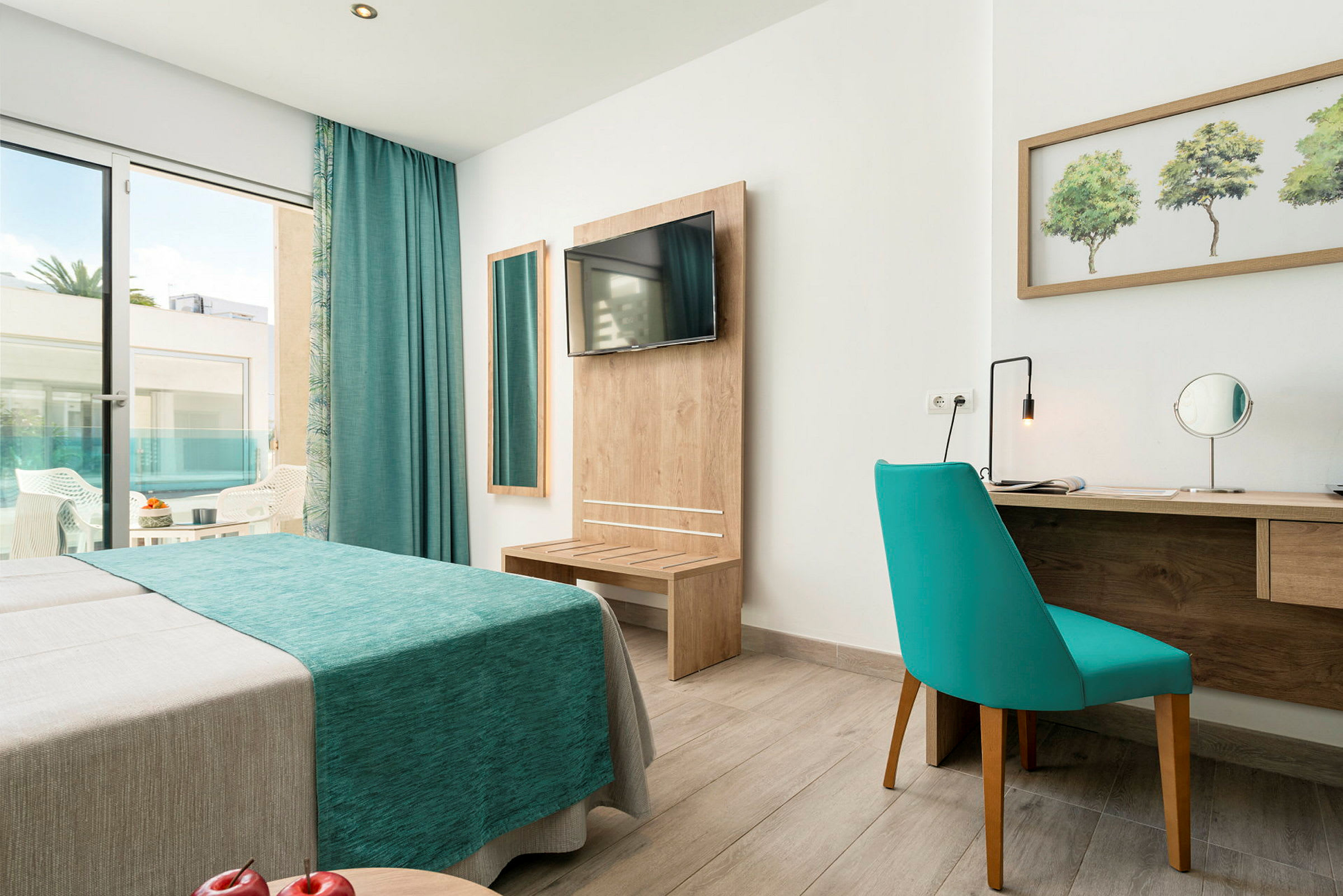 Et hotelværelse med en blå sofa, spejl, skrivebord og udgang til en altan. (AI-genereret tekst)