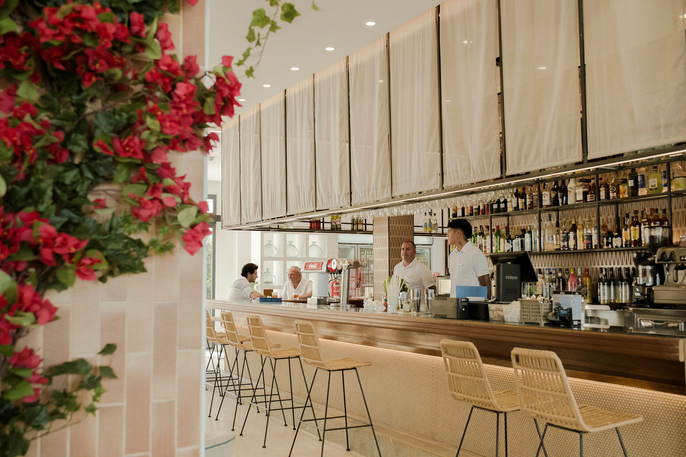 Interiør af en moderne bar med stilfulde møbler og et blomsterbeklædt hjørne. (AI-genereret tekst)