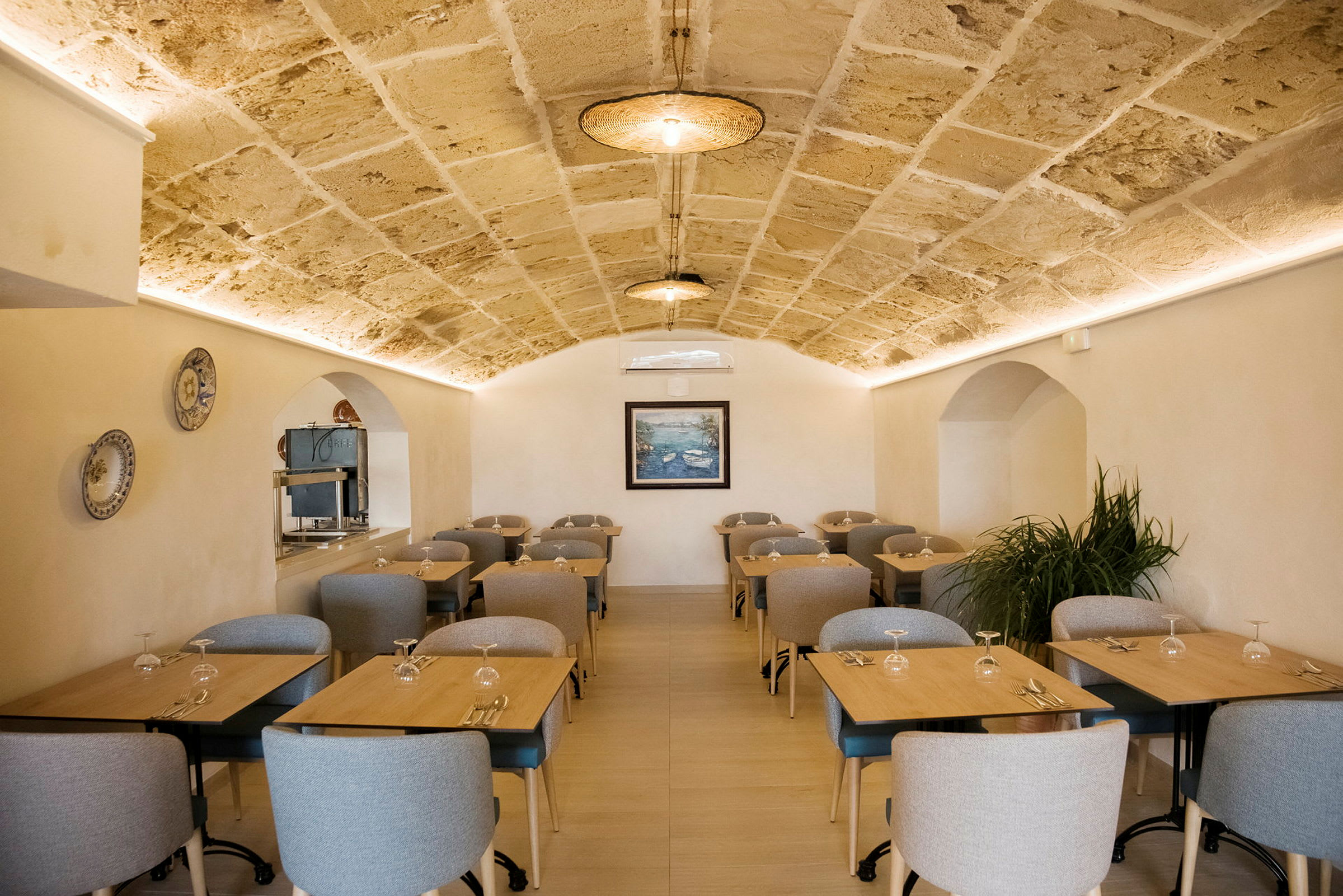 Et restaurantområde med flere borde og stole, samt et hvælvet loft. (AI-genereret tekst)