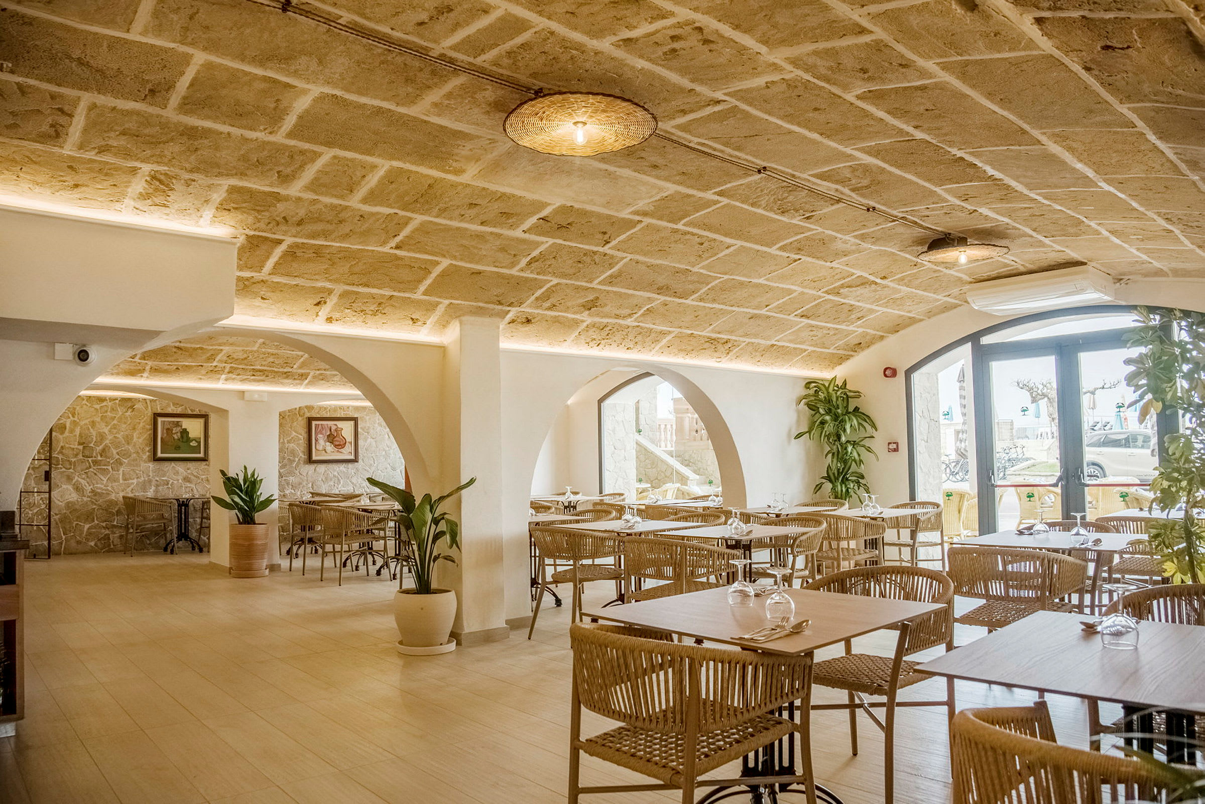 Interiør af en restaurant med stenbuer, moderne møbler og dekorative planter. (AI-genereret tekst)