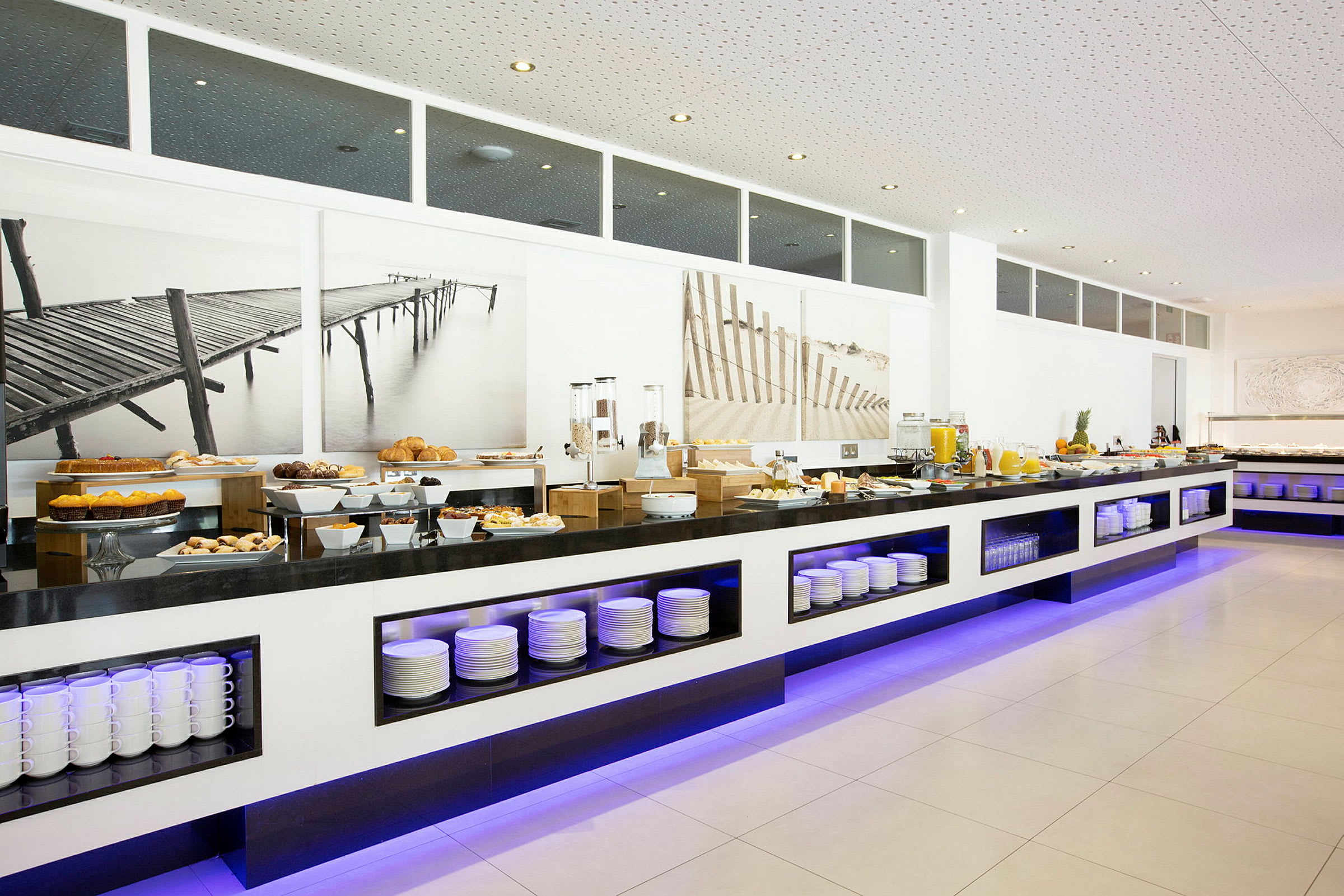 Billede af en morgenmadsbuffet med et udvalg af forskellige retter og drikkevarer arrangeret på en moderne serveringsflade. (AI-genereret tekst)