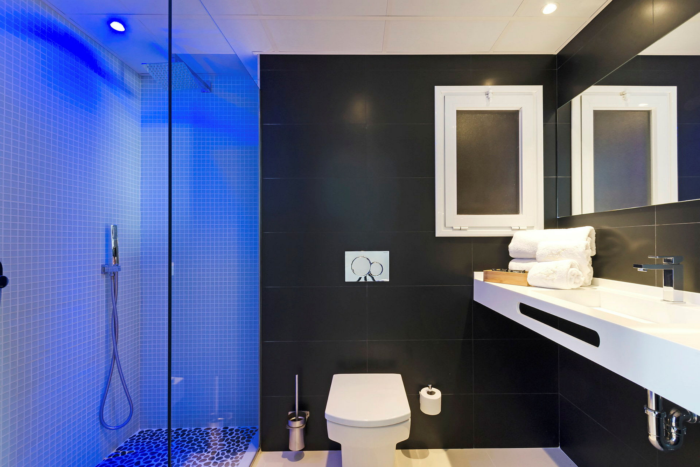 Et moderne badeværelse med bruser, toilet og håndvask samt mørke vægge og hvide detaljer. (AI-genereret tekst)